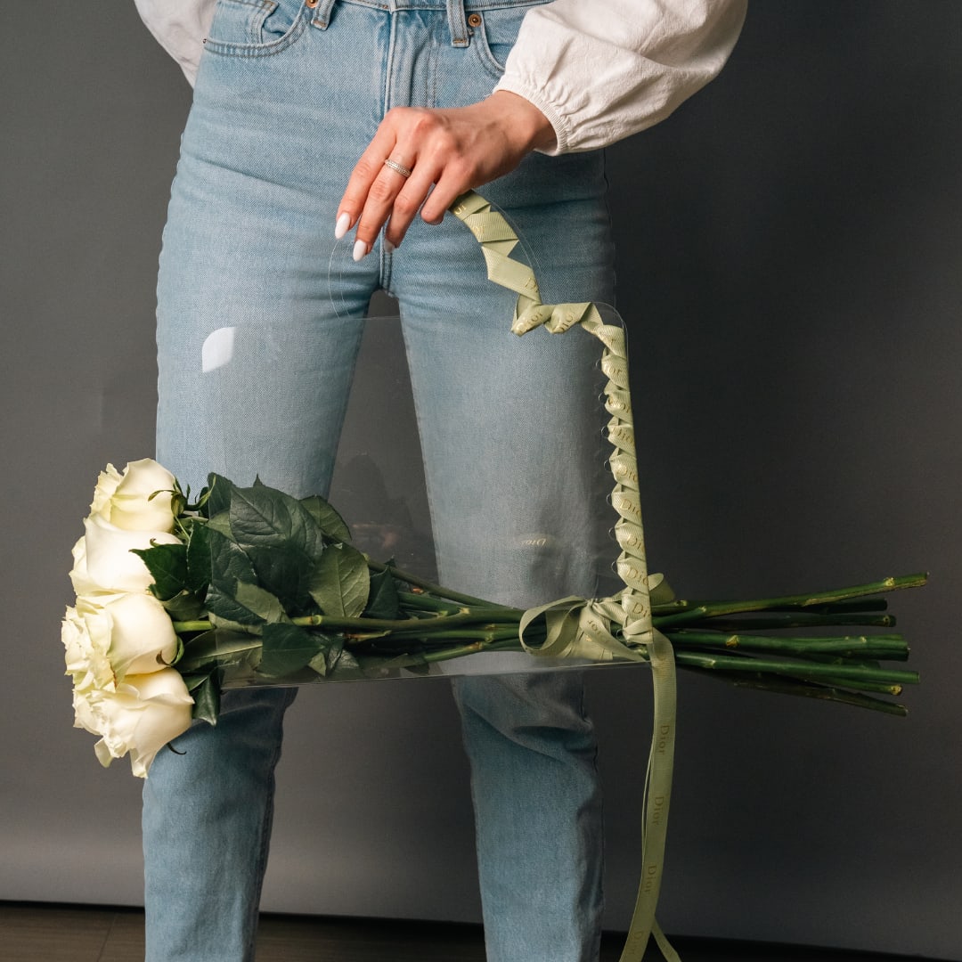 Person holding a bouquet of white roses with a ribbon