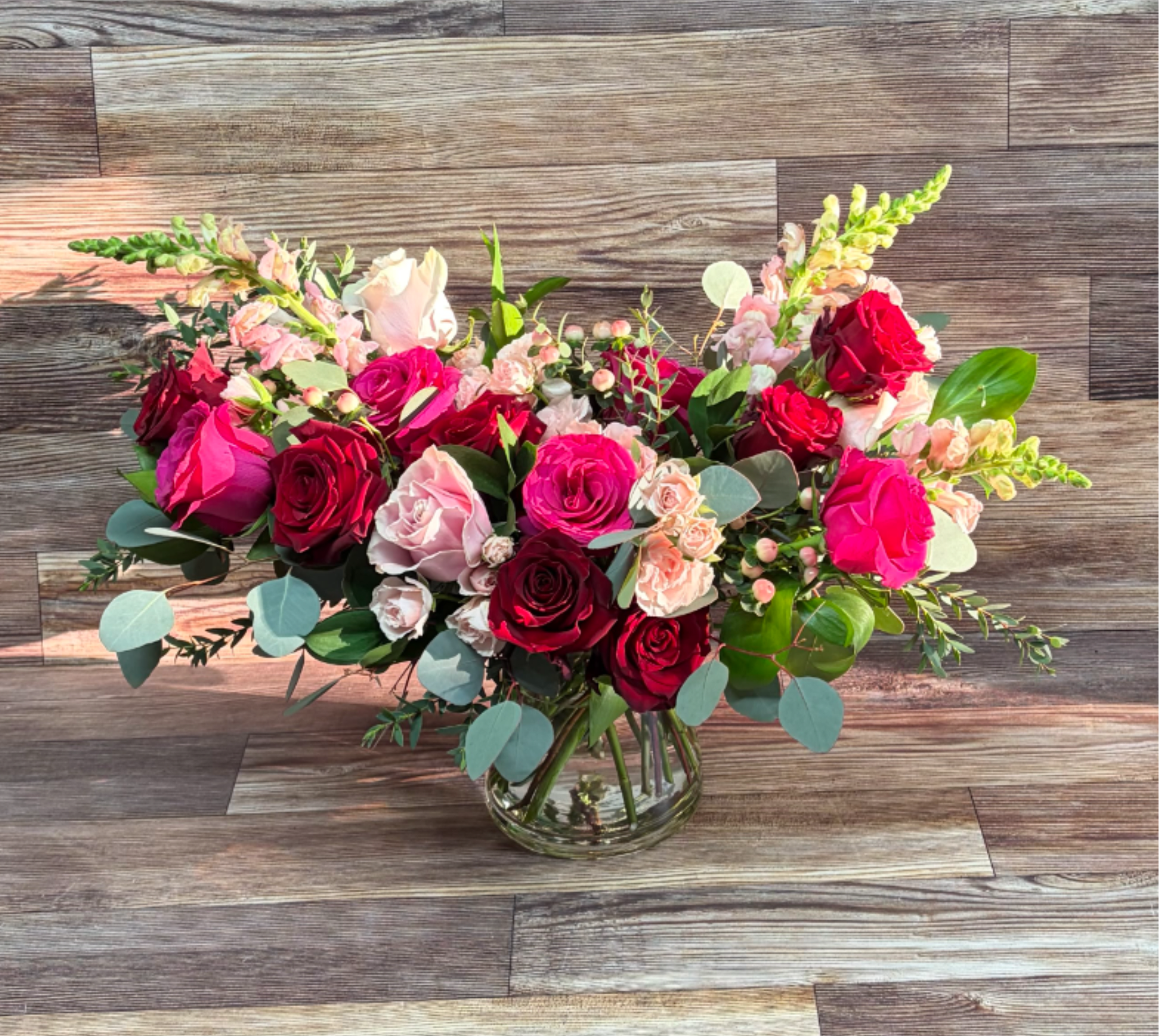 Romantic Heart - A grand combination of 2 dozen red, light pink and hot pink roses, hypericum berries, snapdragons, spray roses and seasonal greens measuring approximately 24 inches wide, 18 inches tall and deep in a heavy duty tapered cylinder vase.