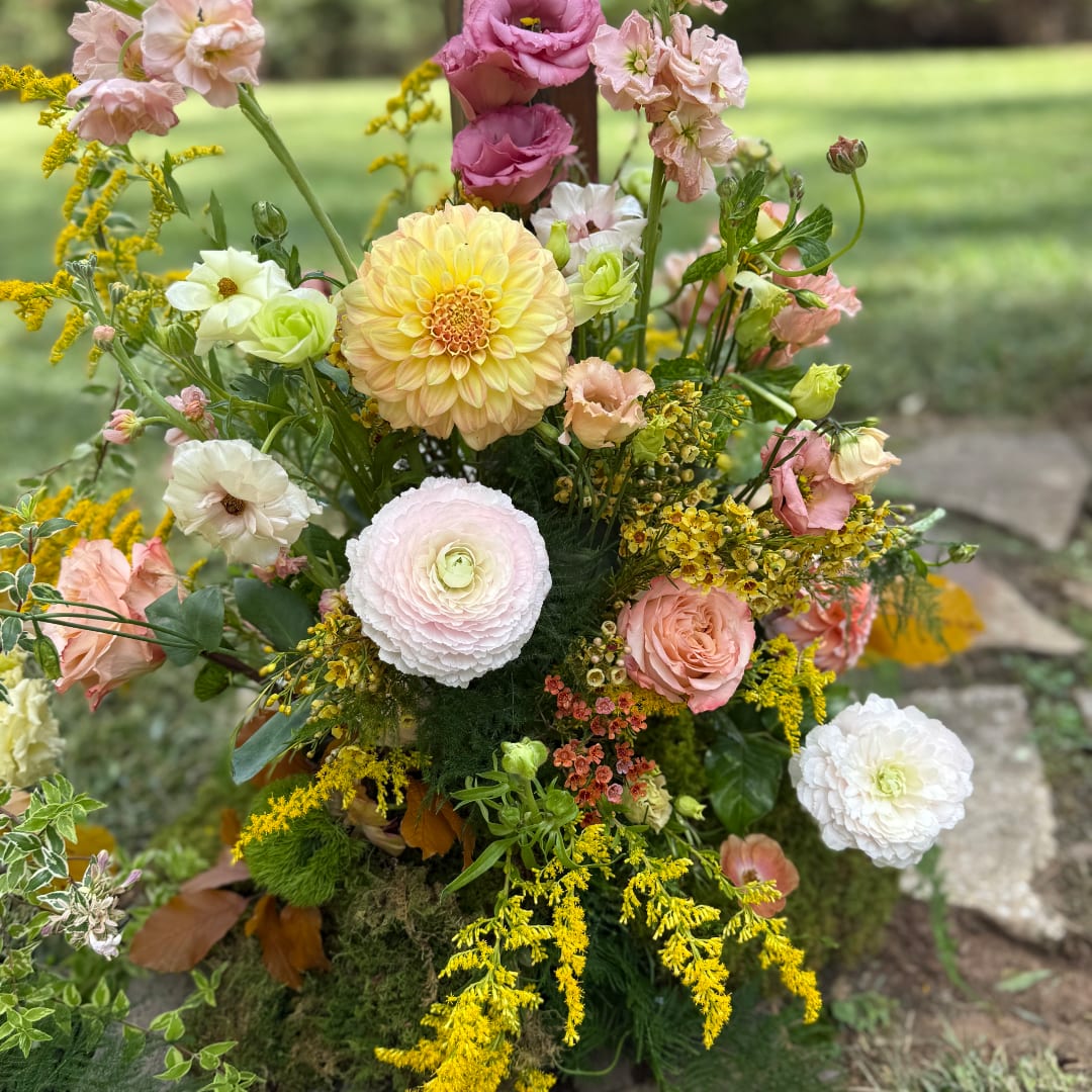 Pastel mixed flower arrangement with dahlias, roses, and ranunculus outdoors