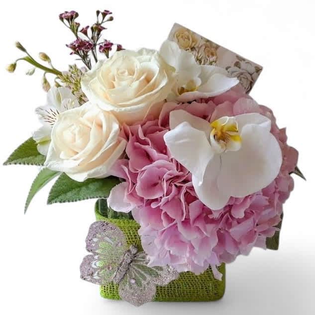 Pink and white floral arrangement in a green wrapped container with a butterfly accent.