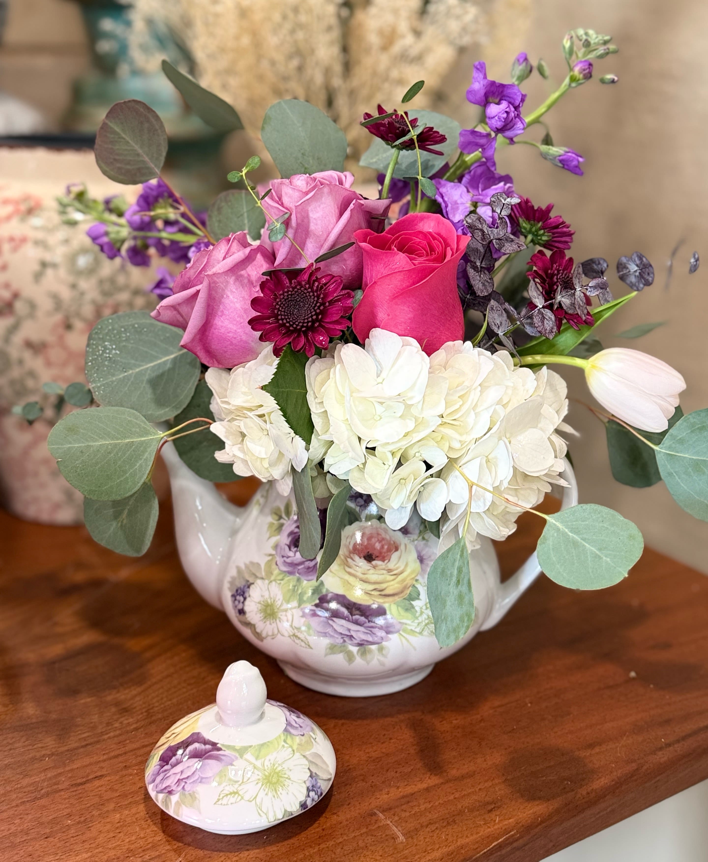 Bouquet of pink and white flowers in a floral teapot vase
