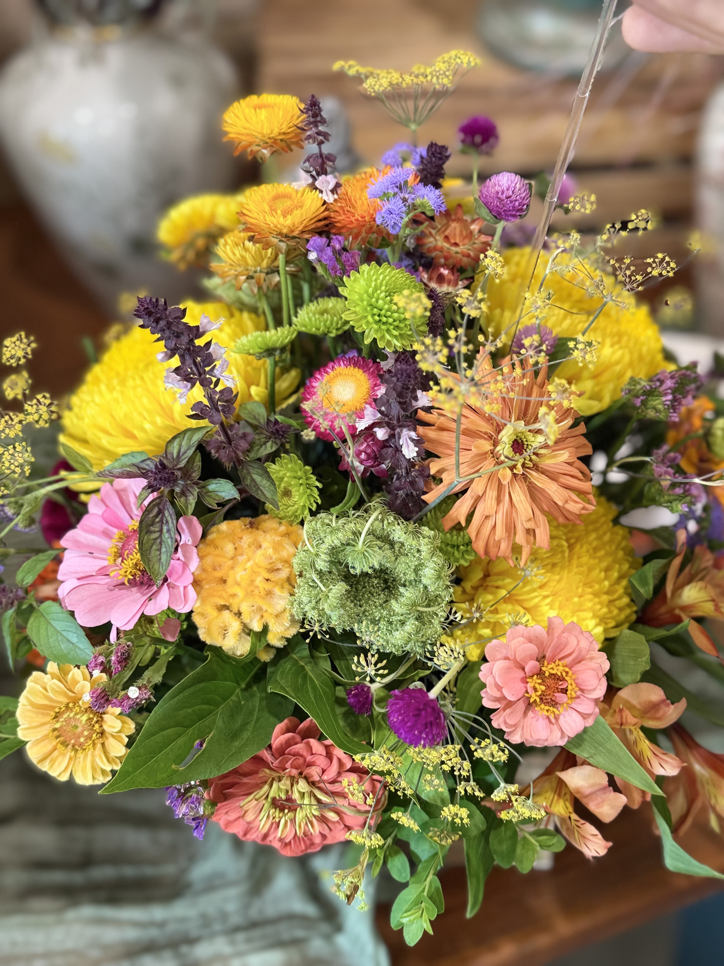 Farmer's Choice Seasonal Arrangement  - A lively, garden-picked mixed bouquet that makes the recipient feel genuinely celebrated-this Farmer's Choice Seasonal Arrangement is a cheerful flower arrangement perfect for birthdays, thank-you gestures, or a bright just-because surprise. Bright yellow, playful pink, warm orange and purple tones combine to create an upbeat, sunny presentation that reads joyful the moment it's placed in a room.   Send this when you want someone to feel seen-an energetic, colorful bouquet that brightens a kitchen table, office desk, or bedside. Care is simple: keep flowers in fresh water, out of direct heat, and trim stems a bit when you refresh the vase to prolong the lively, just-cut look.