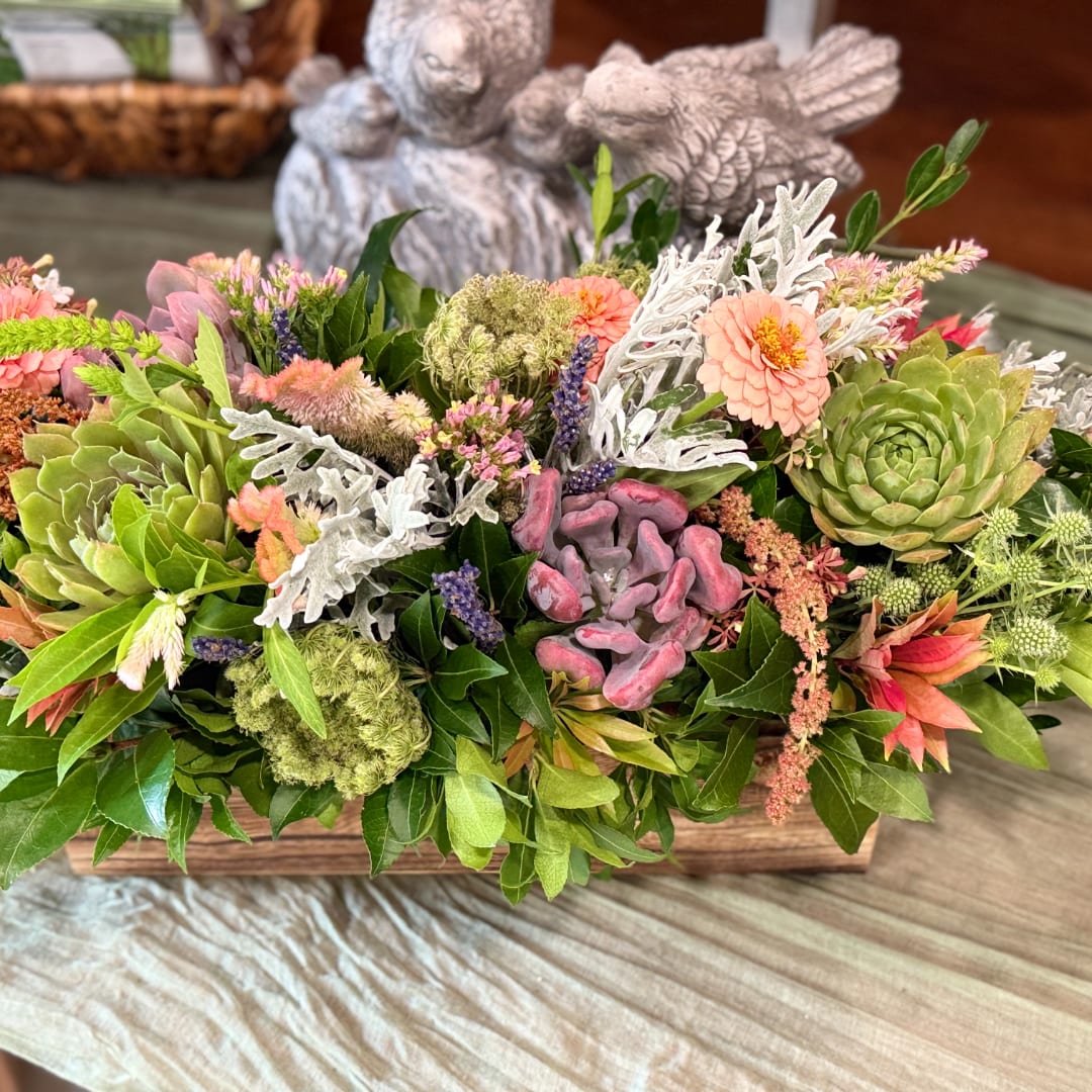 Succulent and flower arrangement in a wooden box with pink blooms