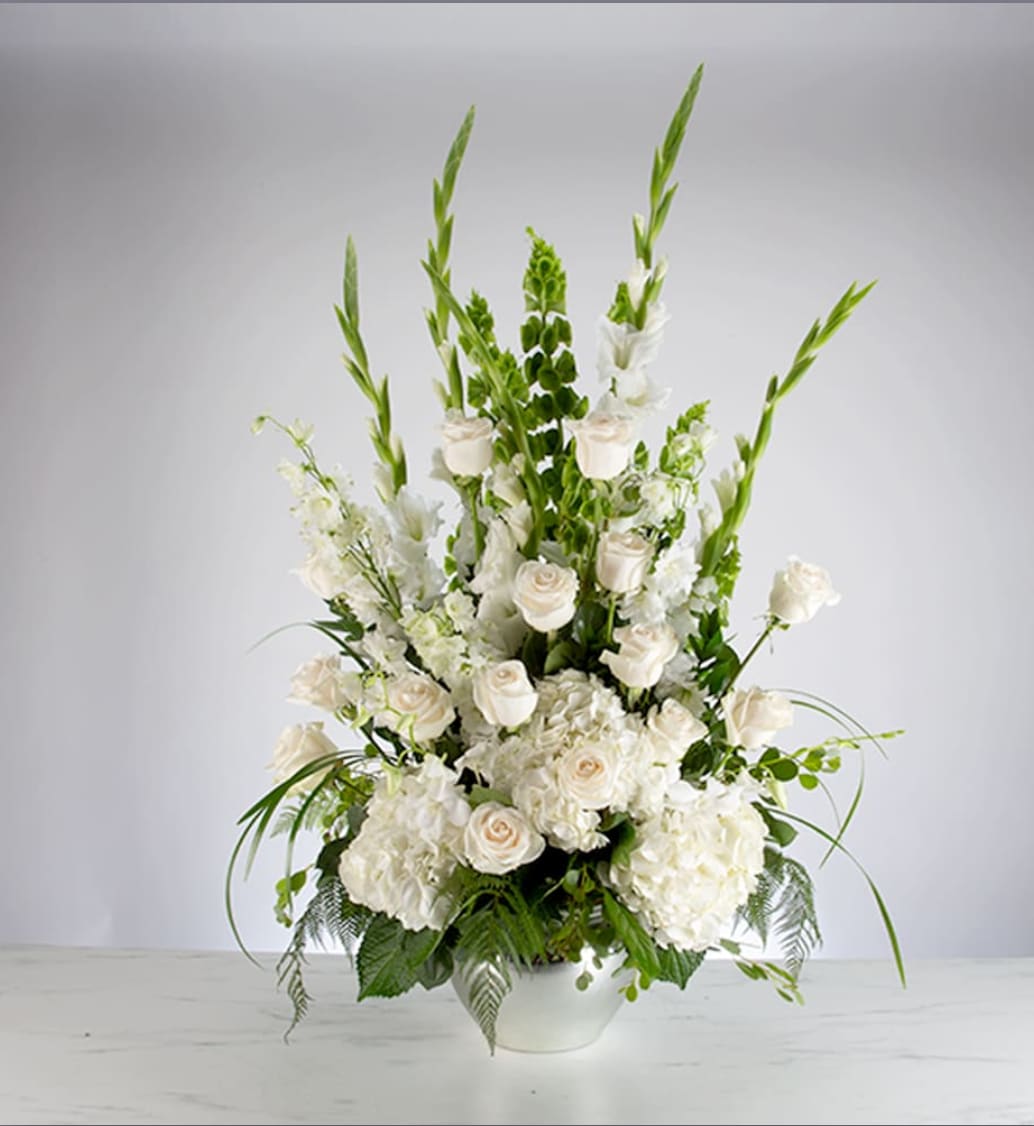 Sweet Comfort  - An all white tribute, this funeral basket is pure and tranquil. Featuring a variety of white flowers and greenery, this design reaches for the sky and evokes a feeling of peace upward and outward. 
