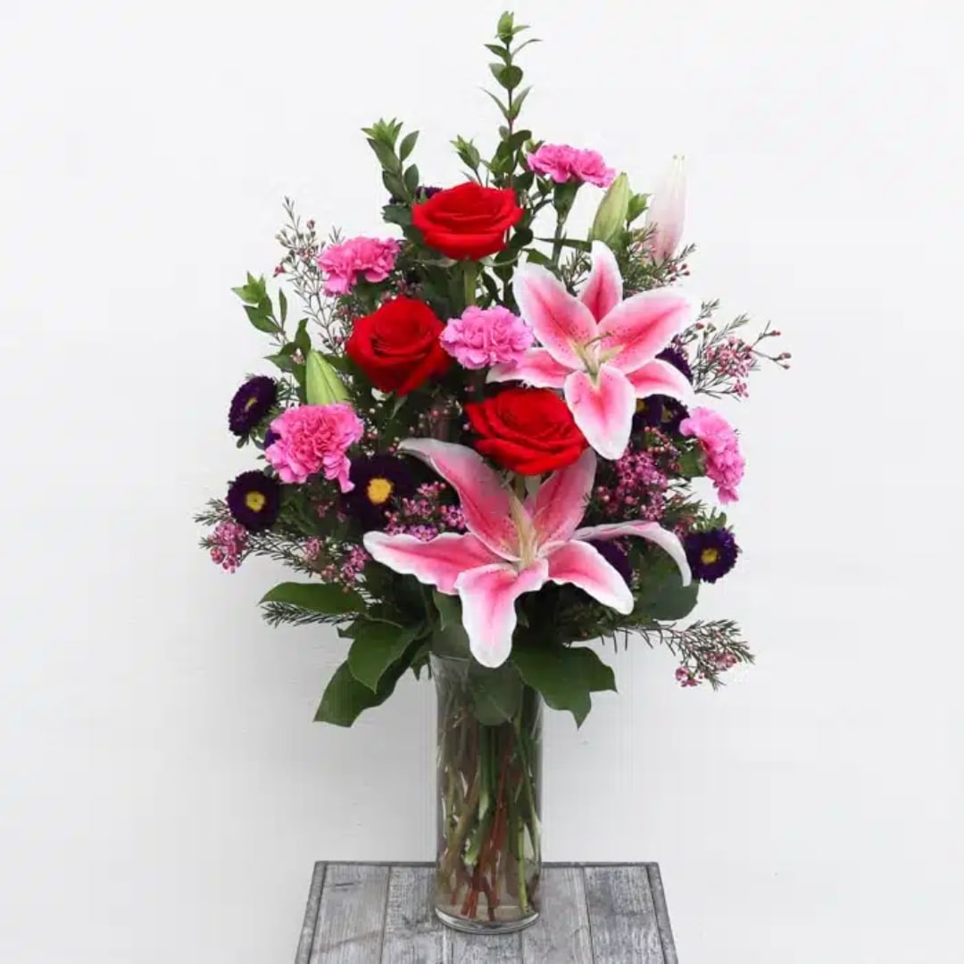 Pink lilies and red roses in a clear glass vase