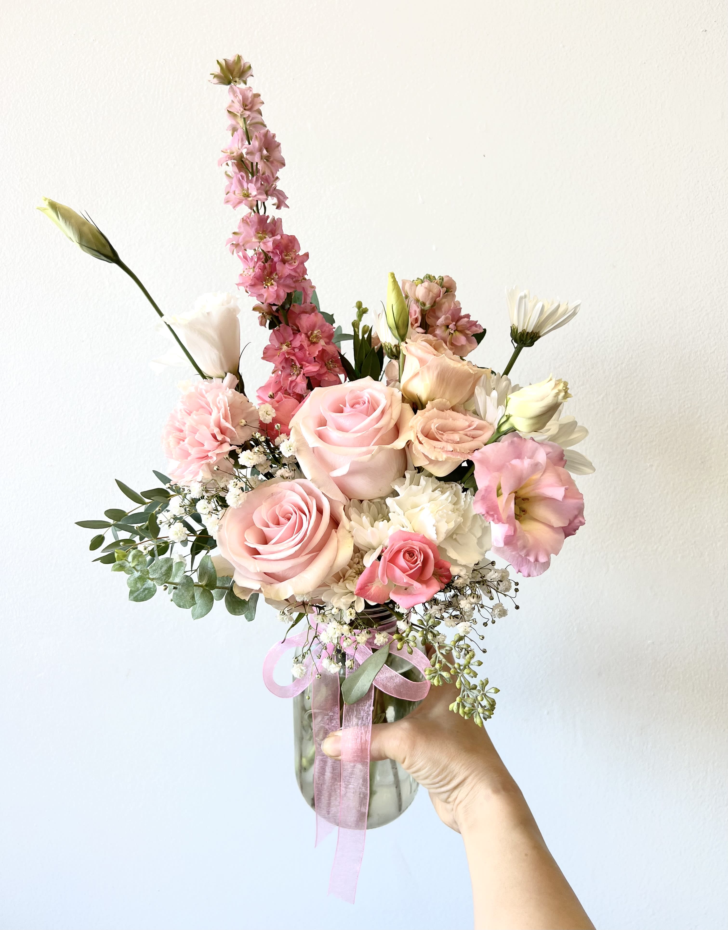 Pink and white bouquet in a glass vase with a pink ribbon