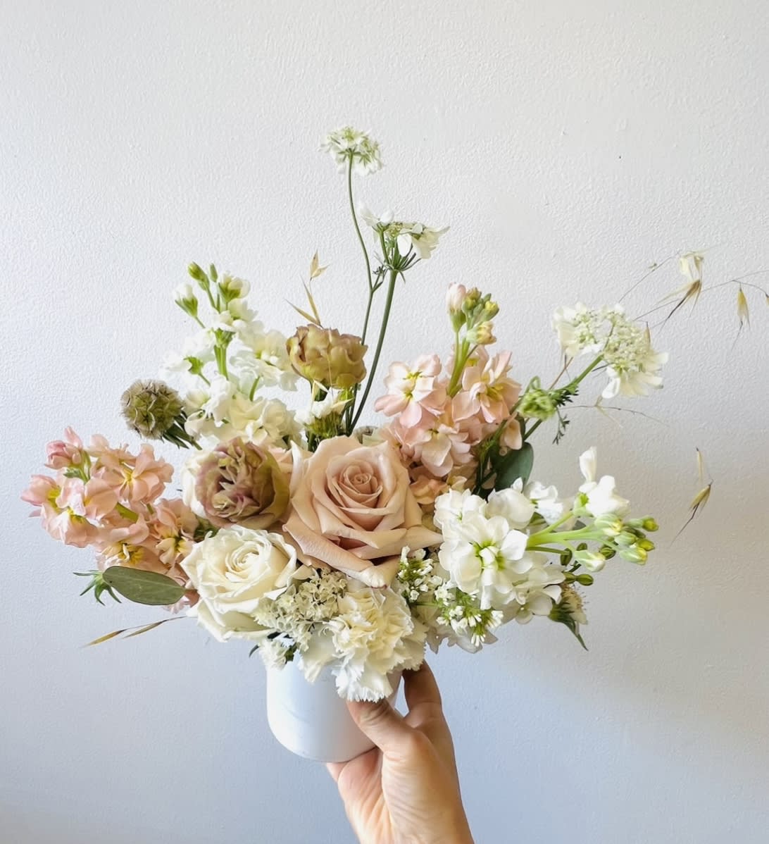 Pastel bouquet of roses and white blooms in a white vase