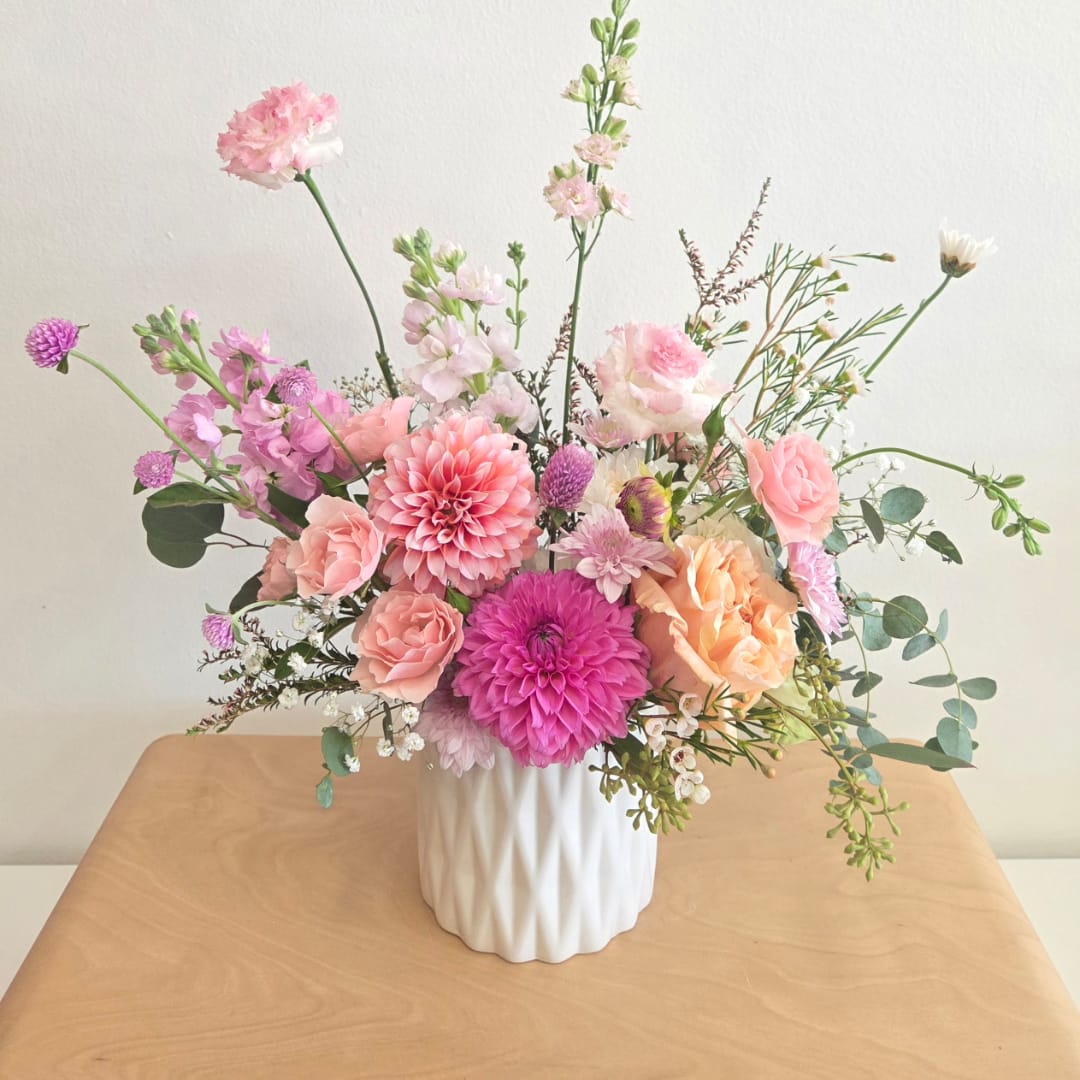 Pink and peach mixed flower arrangement in a white vase
