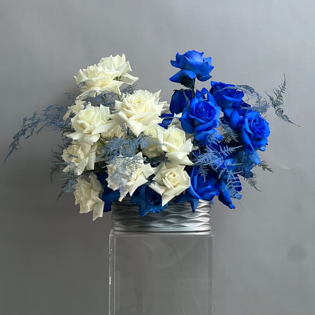 Blue and white roses arranged in a clear vase
