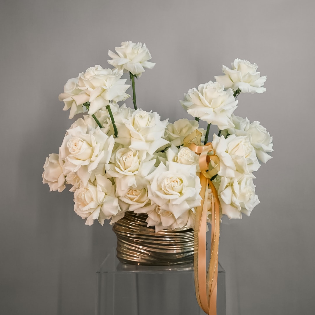 White rose bouquet in a metallic vase with a gold ribbon