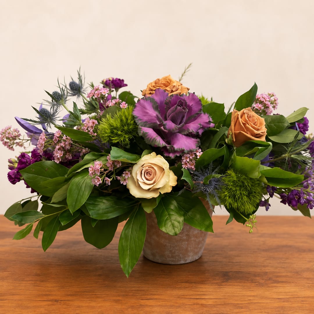 Mixed bouquet in a small pot with purple, peach, and cream flowers