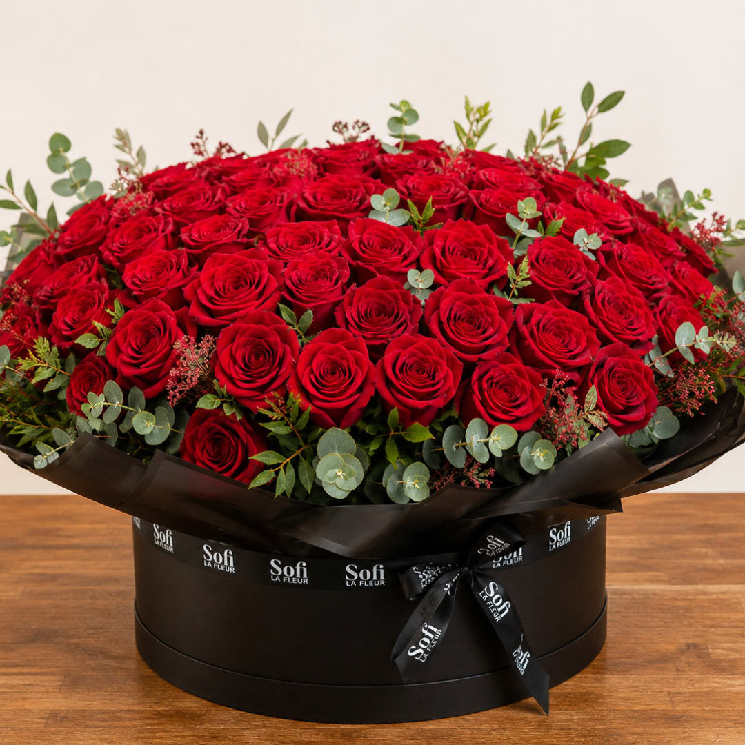 Large round box of red roses with eucalyptus accents