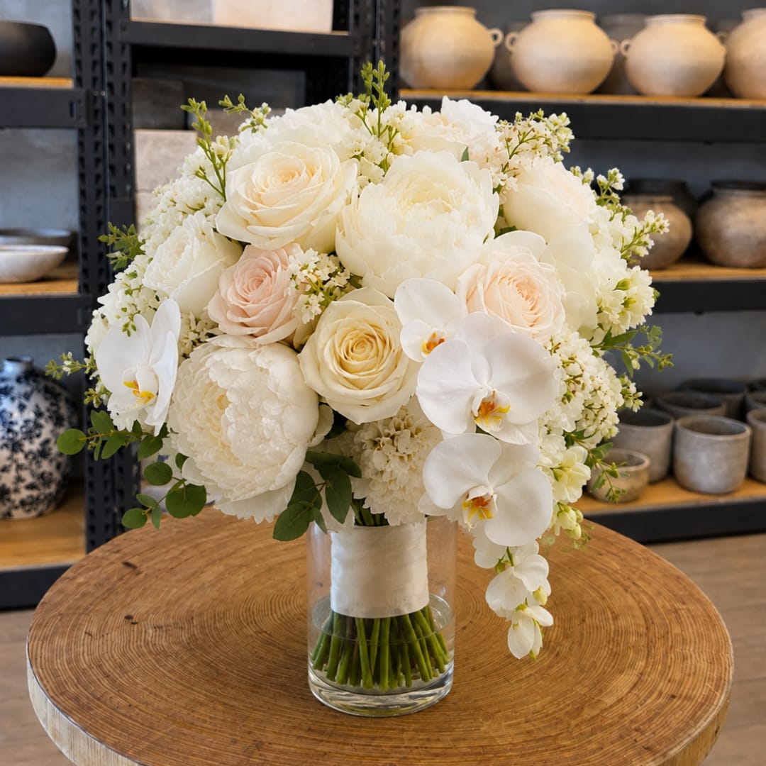 White and blush bridal bouquet in a clear glass vase