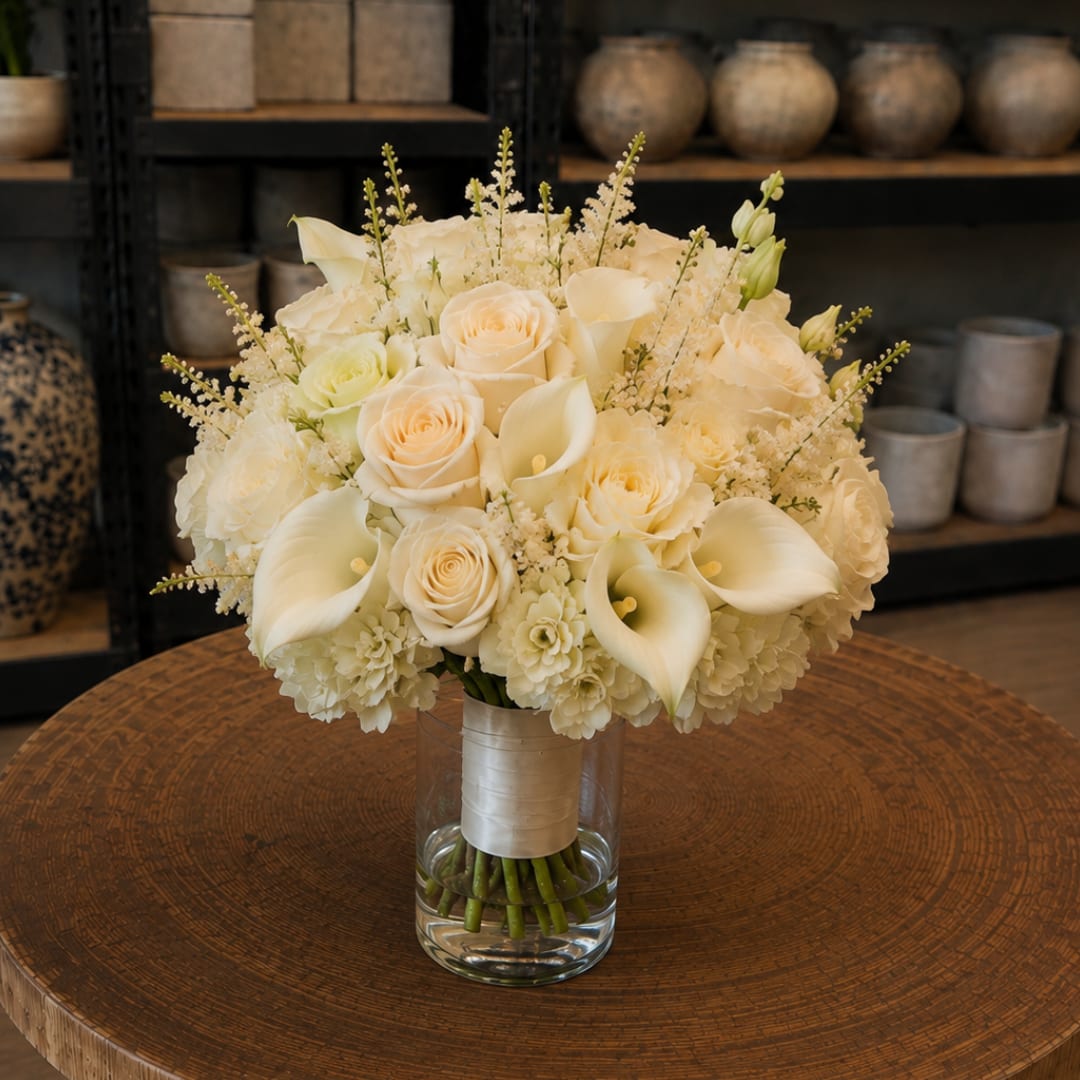 Cream rose and calla lily bouquet in a glass vase