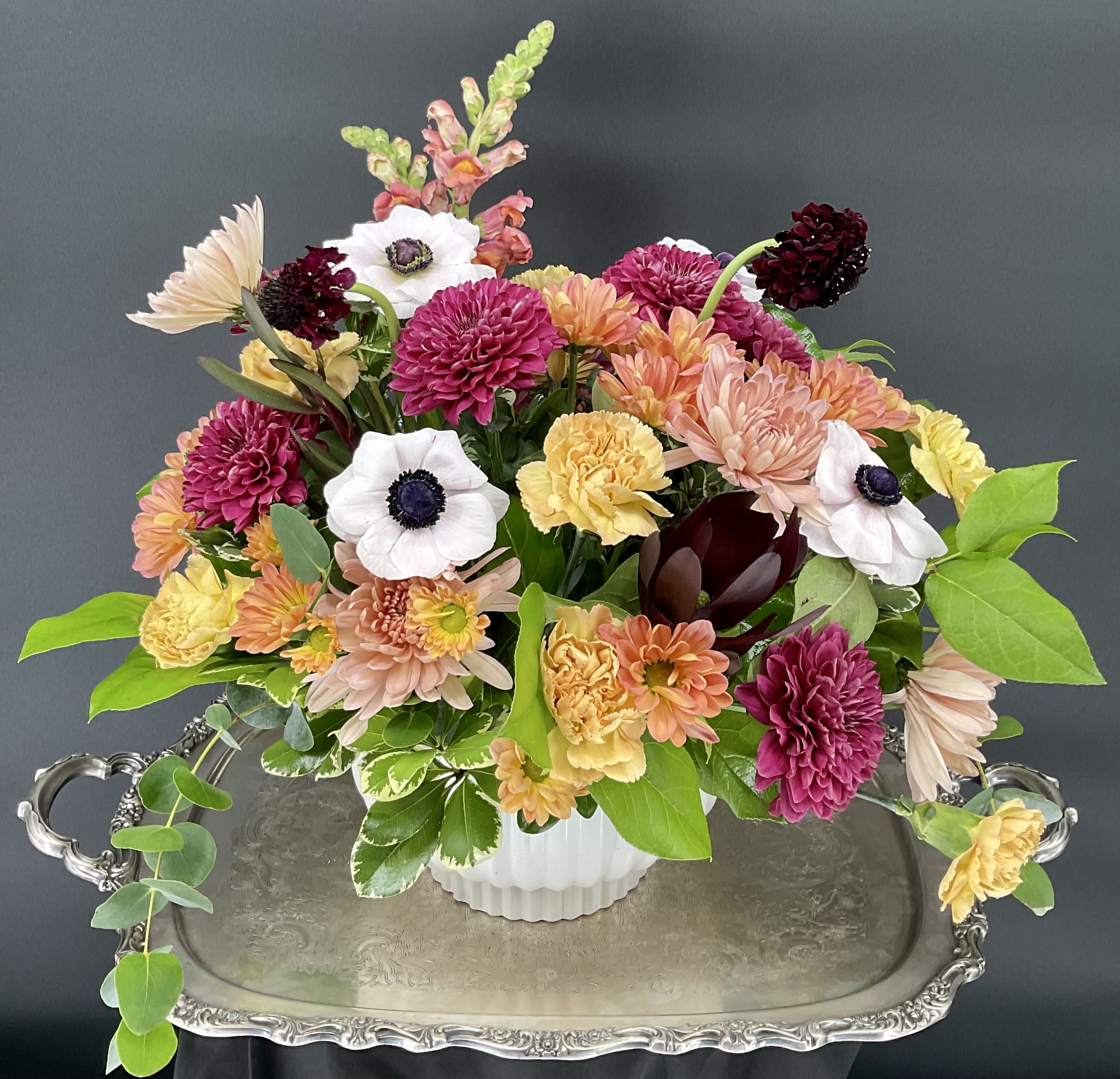Mixed bouquet of chrysanthemums, carnations, and anemones in a white vase