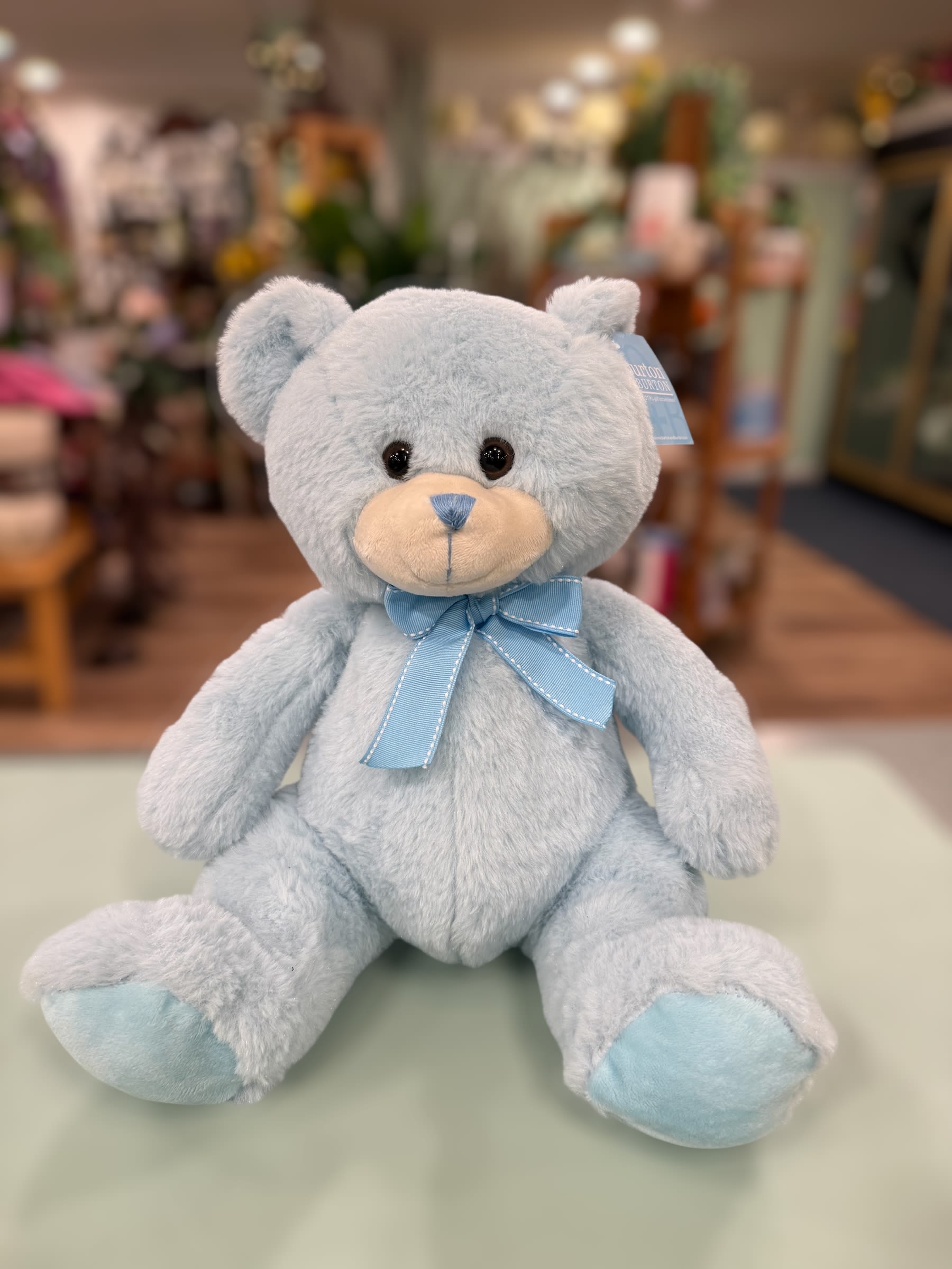 Light blue teddy bear with a ribbon bow sitting on a counter