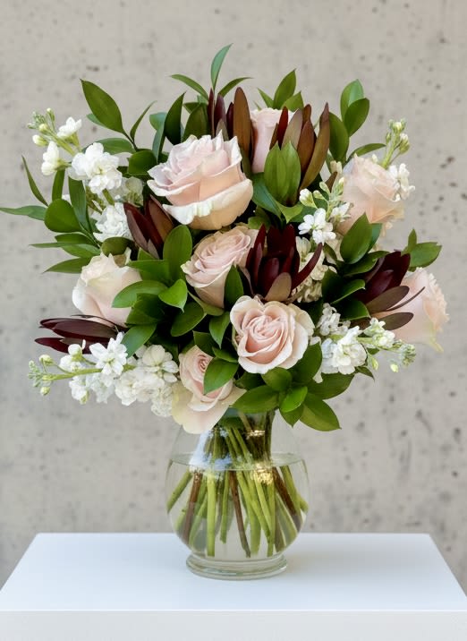 Modern Romance Anniversary 360 Floral Arrangement  - #1 Anniversary Bouquet of Premium Soft Pink Ruffle Roses, Burgundy Luecadendron, White Stock and Dark Greens in a full 360 arrangement - in a an elegant Bella 9" Vase.