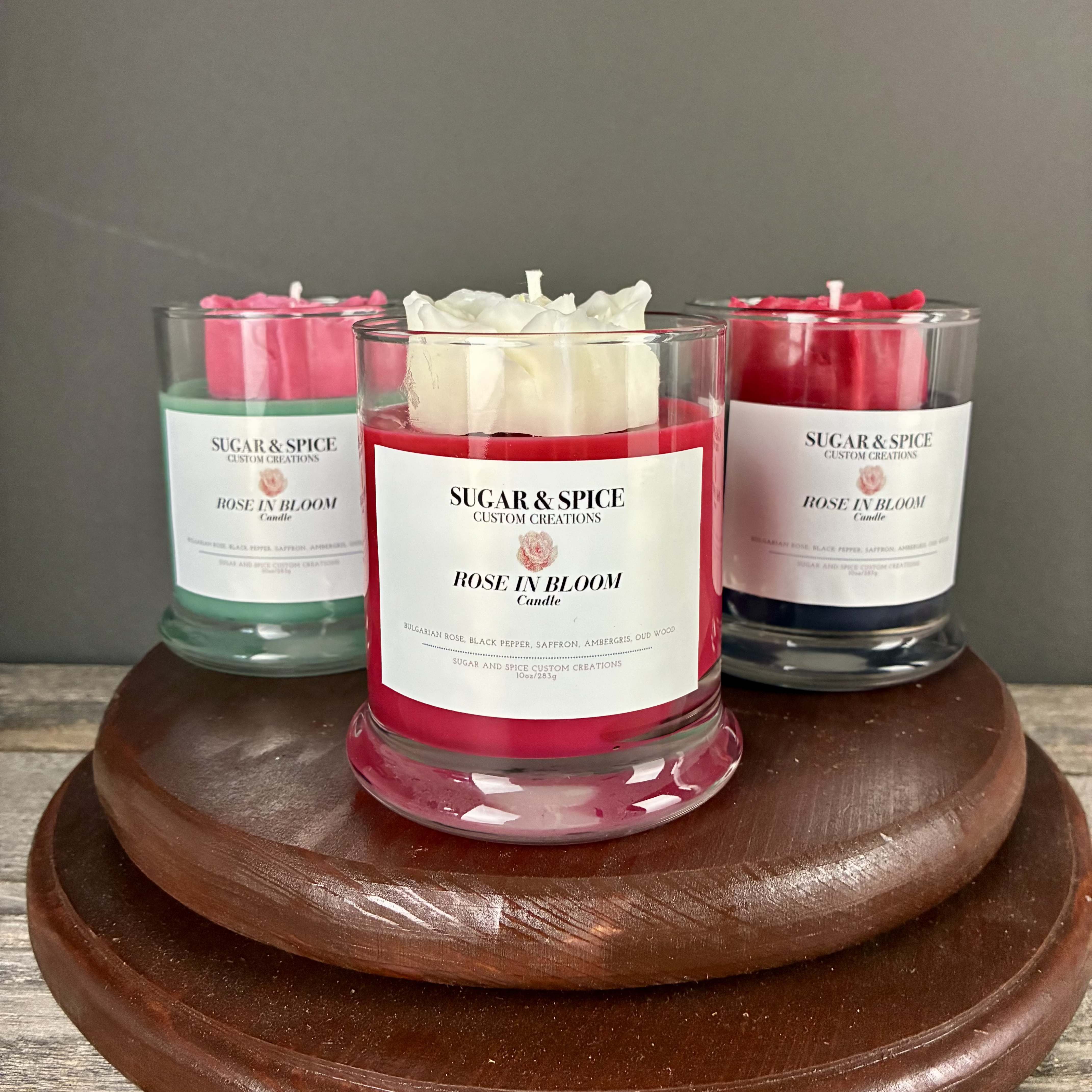 Rose In Bloom Candle - This sweet smelling candle with a hand made wax rose on top has notes of Bulgarian rose, black pepper, saffron, ambergris, and oud wood. Only sold here at Renee's!