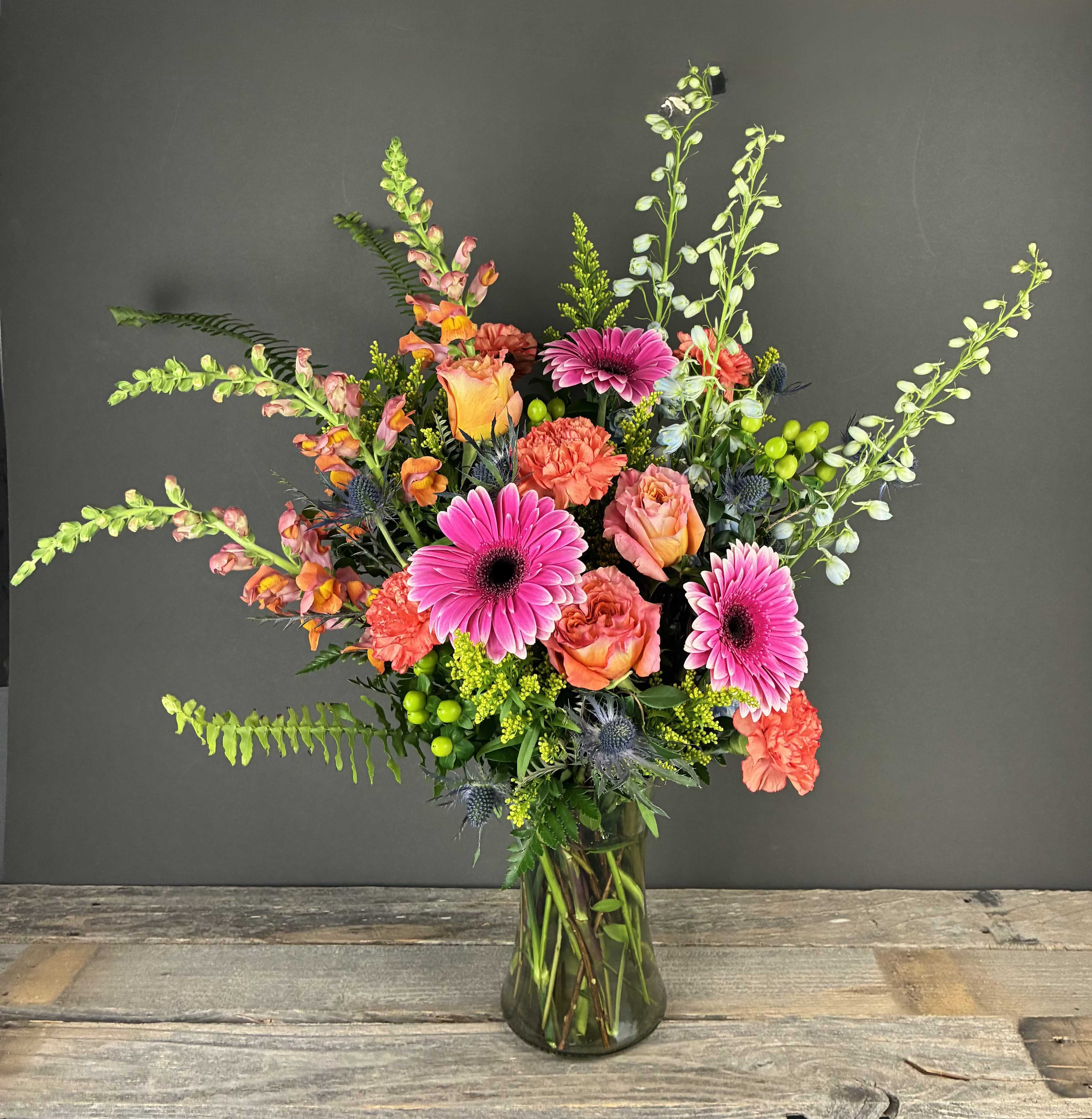 Mixed bouquet of pink gerbera daisies and orange roses in a glass vase