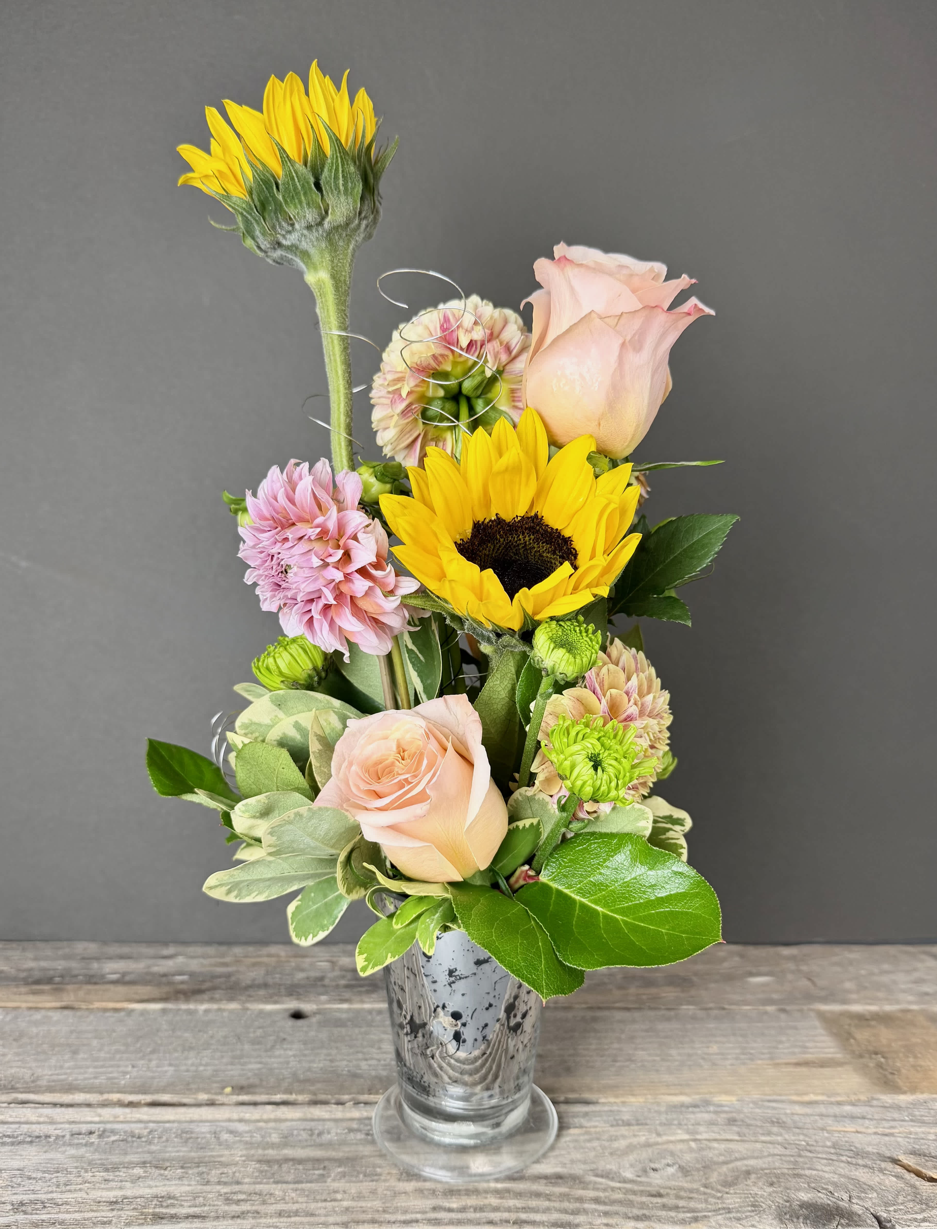 Mixed bouquet with sunflowers, pale pink roses, and chrysanthemums in a glass vase