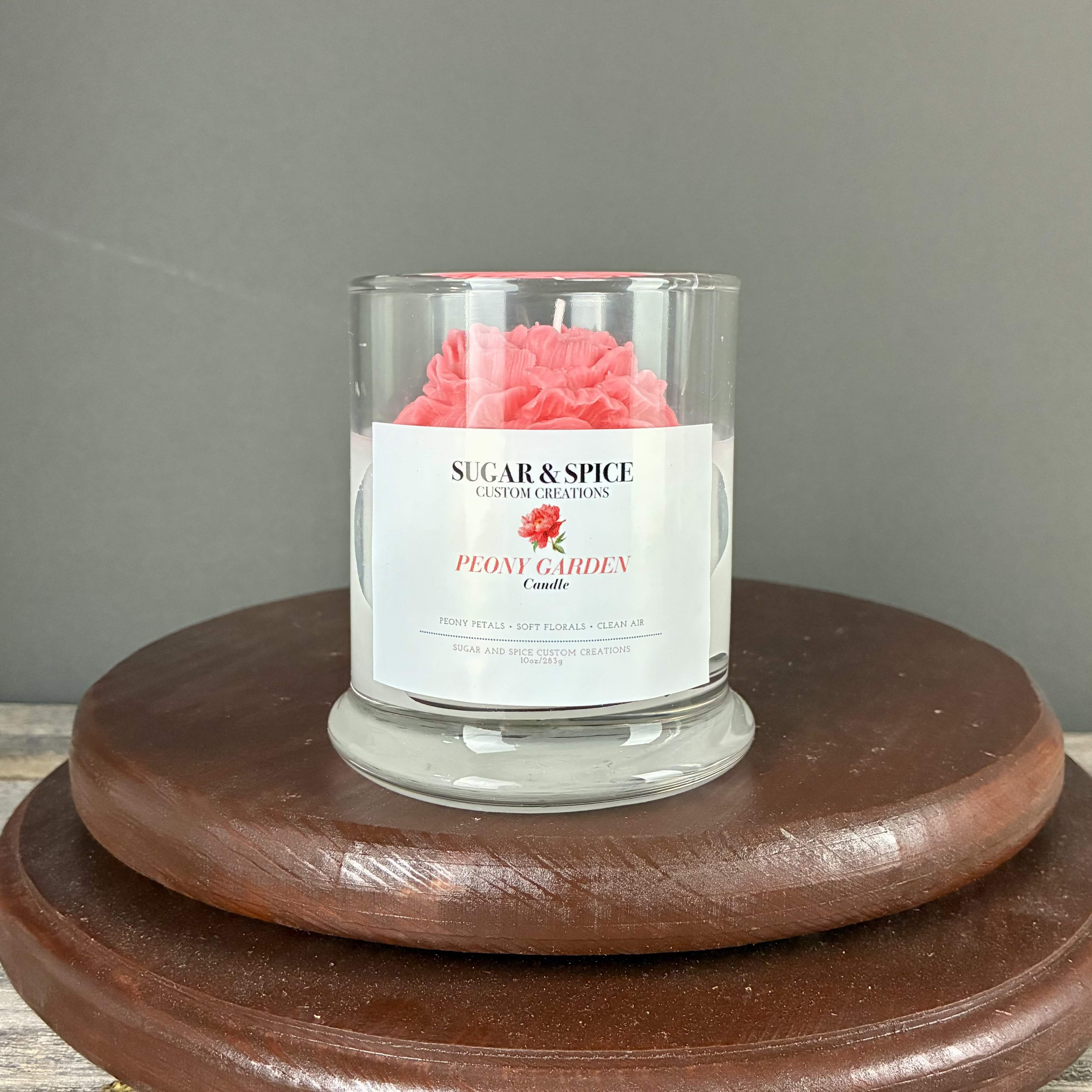 Glass Peony Garden candle with pink wax flower on a wooden stand
