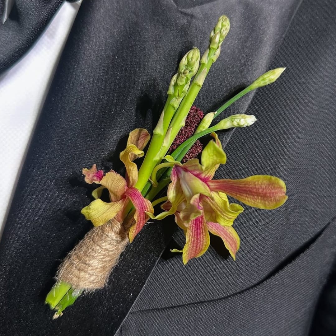 Boutonniere with green orchid blooms on a black suit jacket