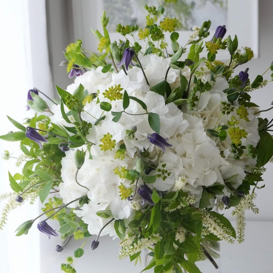 White hydrangea bouquet with purple bell-shaped flowers and green accents