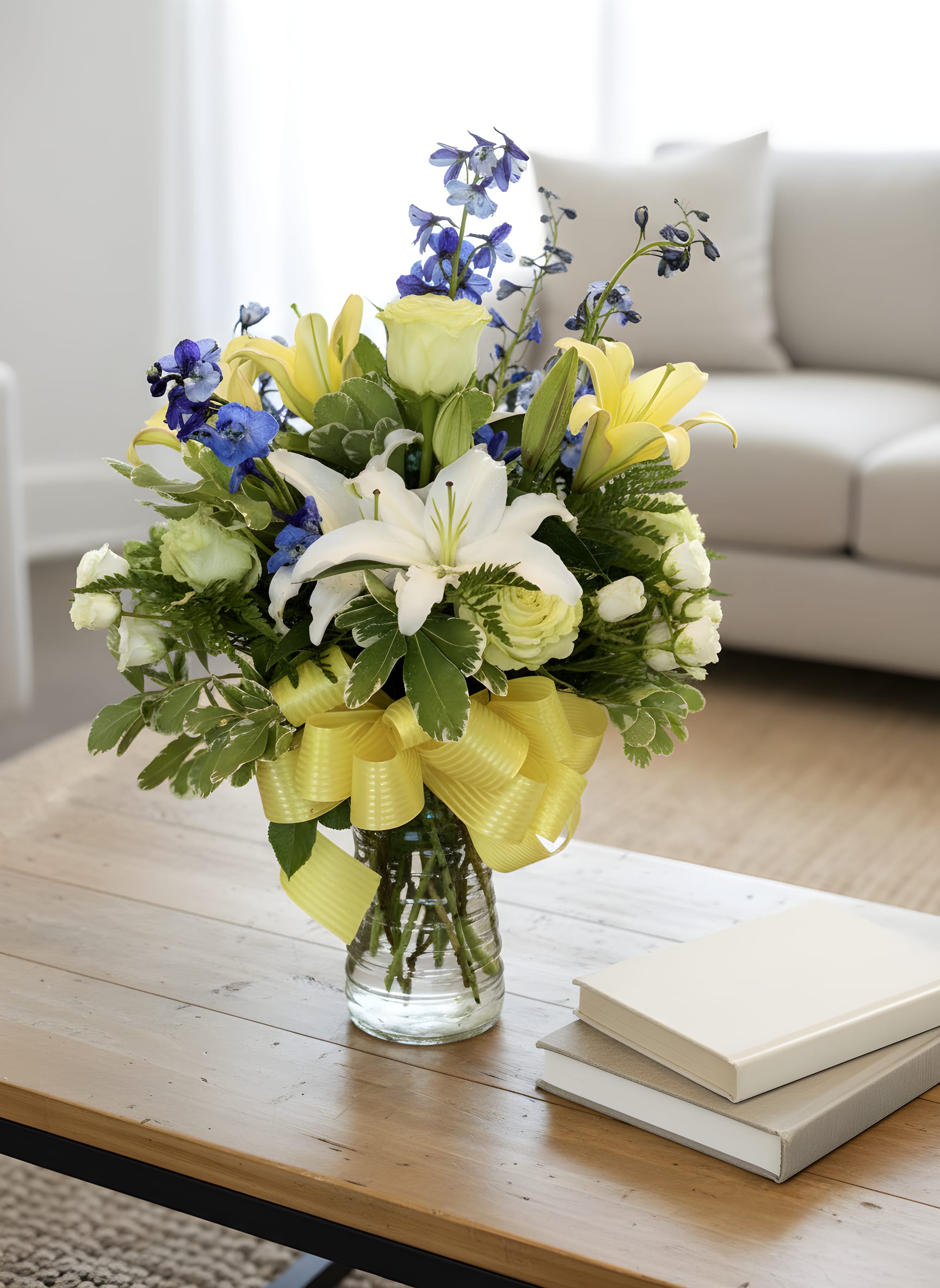Blue Skies &amp; Sunshine™ Bouquet - Brighten someone’s day with our Blue Skies &amp; Sunshine™ Bouquet, a fresh and vibrant arrangement featuring fragrant white lilies, sunny yellow lilies, elegant white roses, delicate spray roses, striking blue delphinium, and premium seasonal greenery.  Handcrafted in a classic glass vase and finished with a cheerful yellow ribbon, this bouquet brings warmth, hope, and happiness to any occasion. Whether you’re celebrating a birthday, welcoming a new baby, sending get well wishes, or simply letting someone know you’re thinking of them, this beautiful design is sure to leave a lasting impression.  Each arrangement is carefully designed by the floral artists at Tommy Austin Florist using only the freshest flowers available.