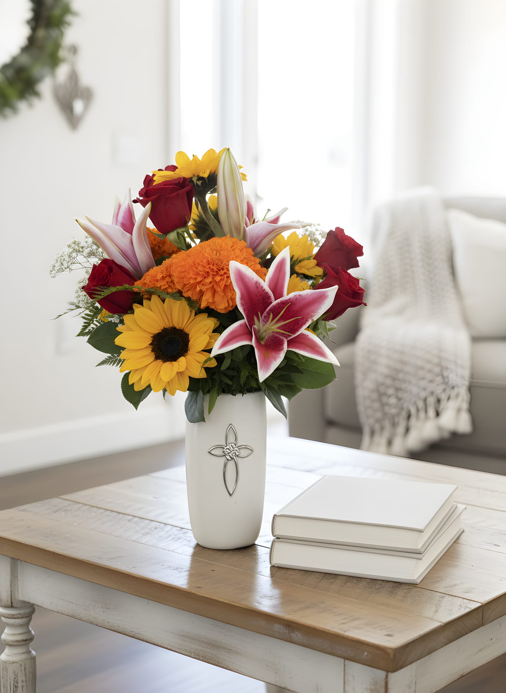 Heaven’s Promise™ Cross Vase Arrangement - Honor a cherished life and offer comfort with our Heaven’s Promise™ Cross Vase Arrangement. This heartfelt design features radiant sunflowers, fragrant pink Stargazer lilies, classic red roses, vibrant orange carnations, cheerful yellow daisies, delicate baby’s breath, and lush seasonal greenery, beautifully arranged in a keepsake white ceramic vase adorned with an elegant silver cross.  The vibrant colors symbolize hope, faith, love, and the joyful memories that live on forever. Long after the flowers have faded, the beautiful cross vase becomes a treasured keepsake, serving as a lasting reminder of your love and support.  Handcrafted by the caring floral designers at Tommy Austin Florist, this arrangement is designed to bring peace and comfort during life’s most meaningful moments.