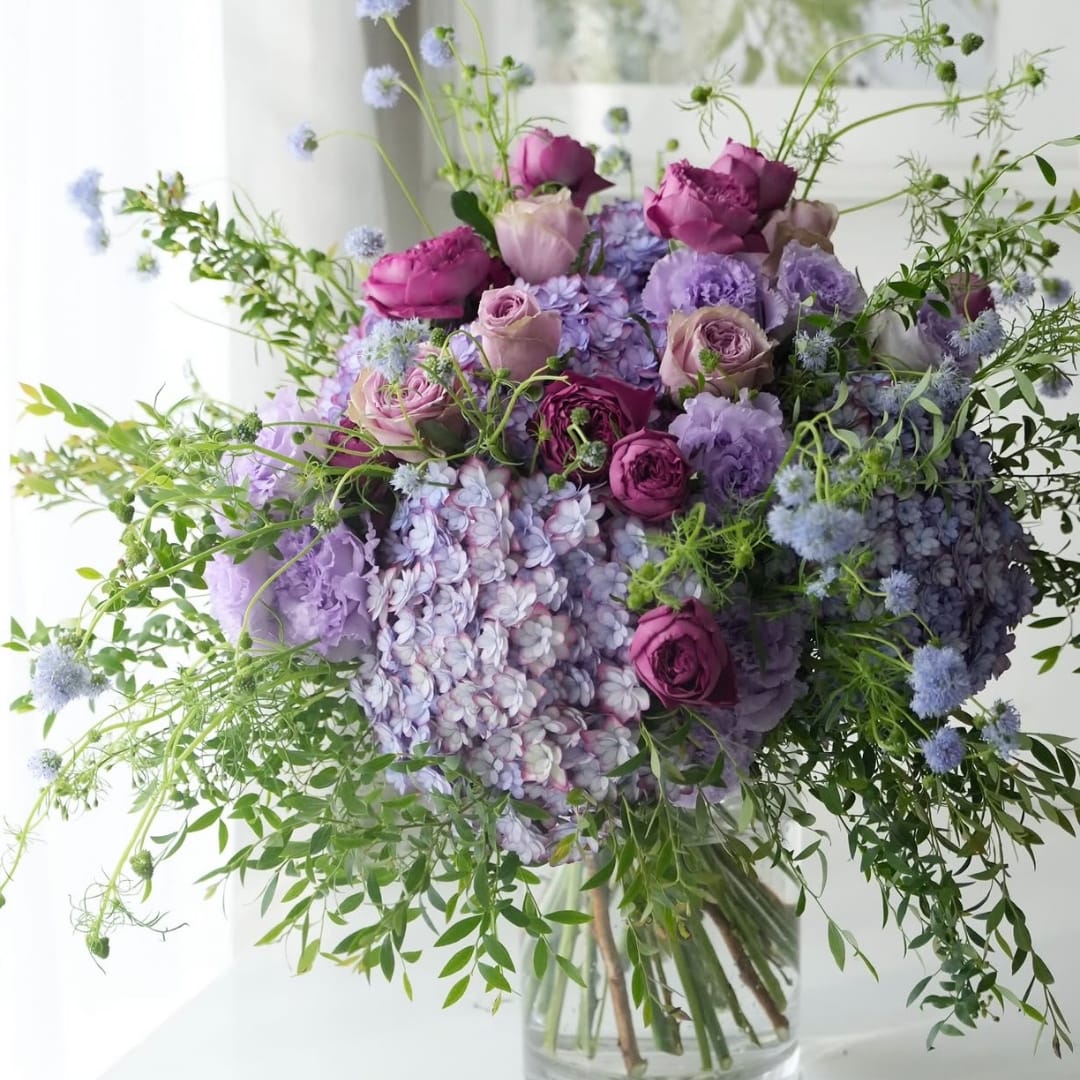 Lavender and purple bouquet with roses and hydrangeas in a clear vase