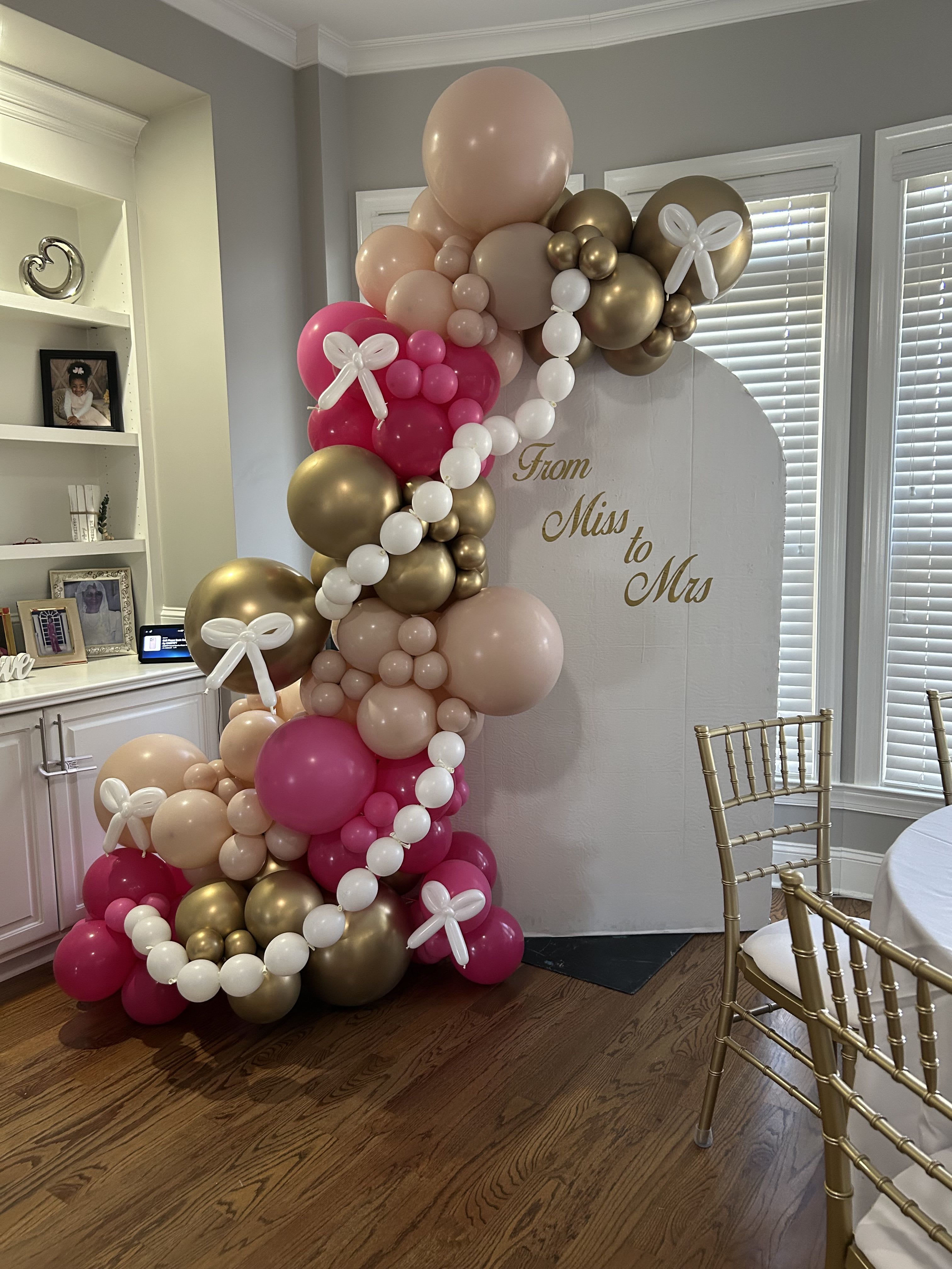 Pink, gold, and white balloon arch around a "From Miss to Mrs" sign