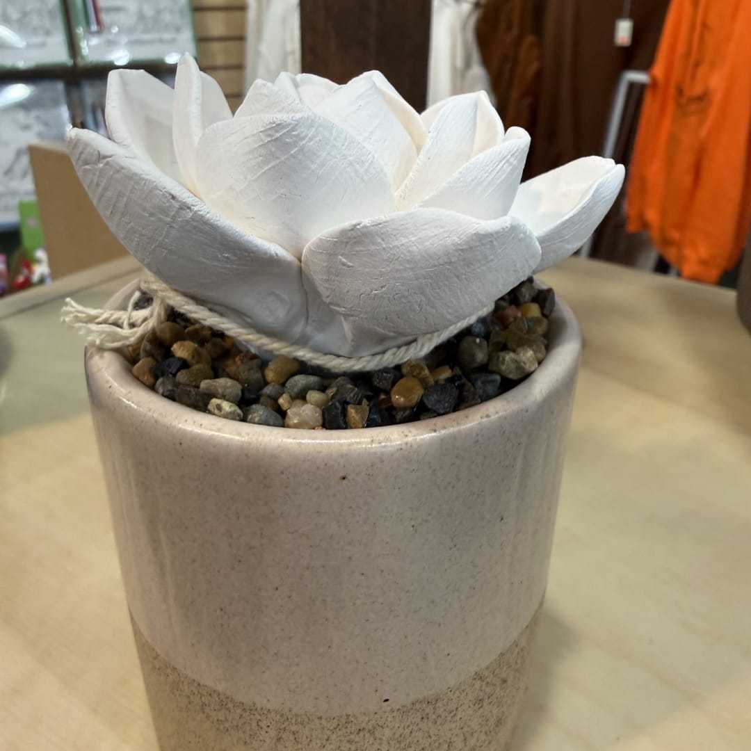 White lotus-shaped decor in a beige ceramic pot with pebbles