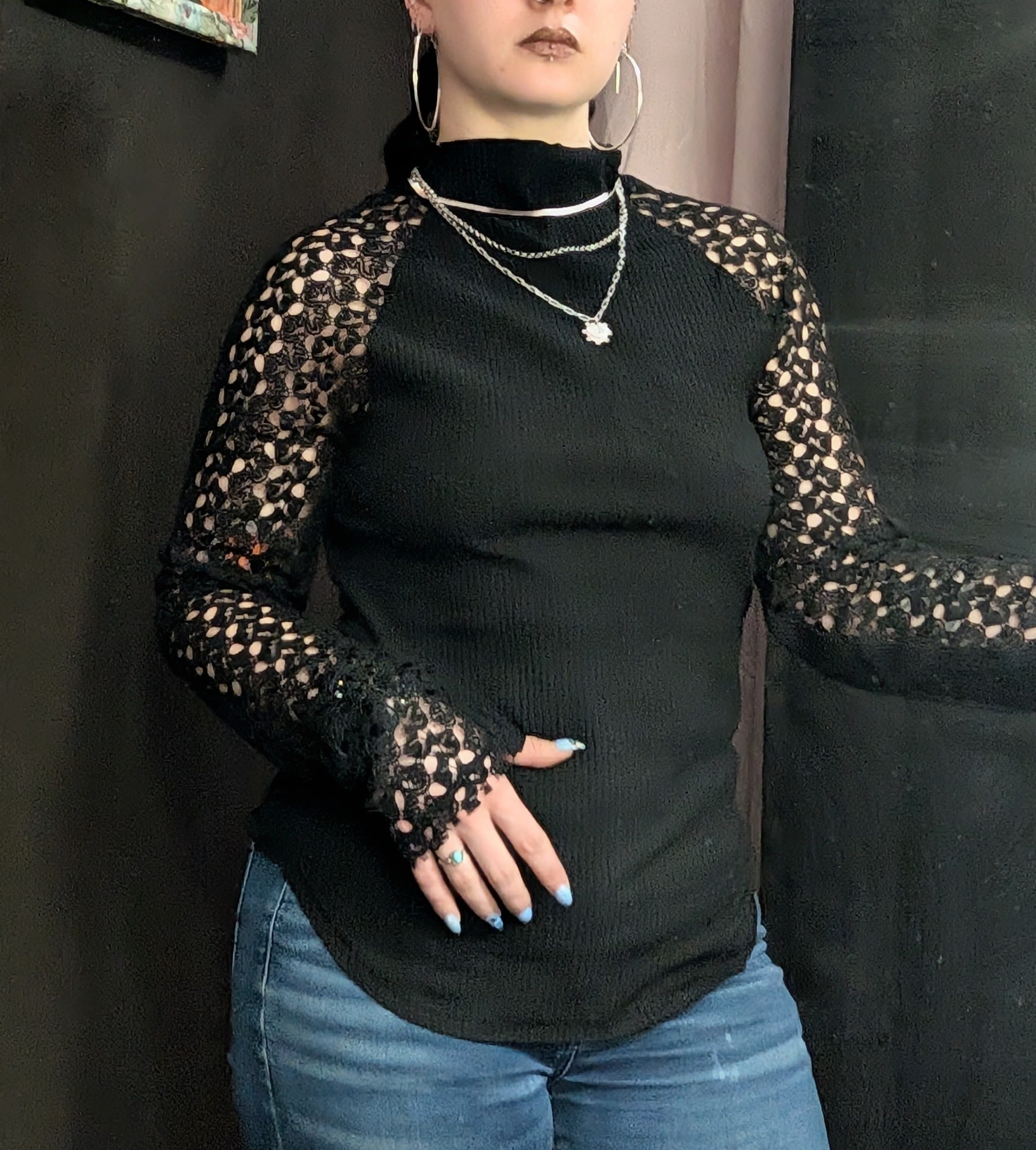 Person wearing a black lace-sleeve top and jeans
