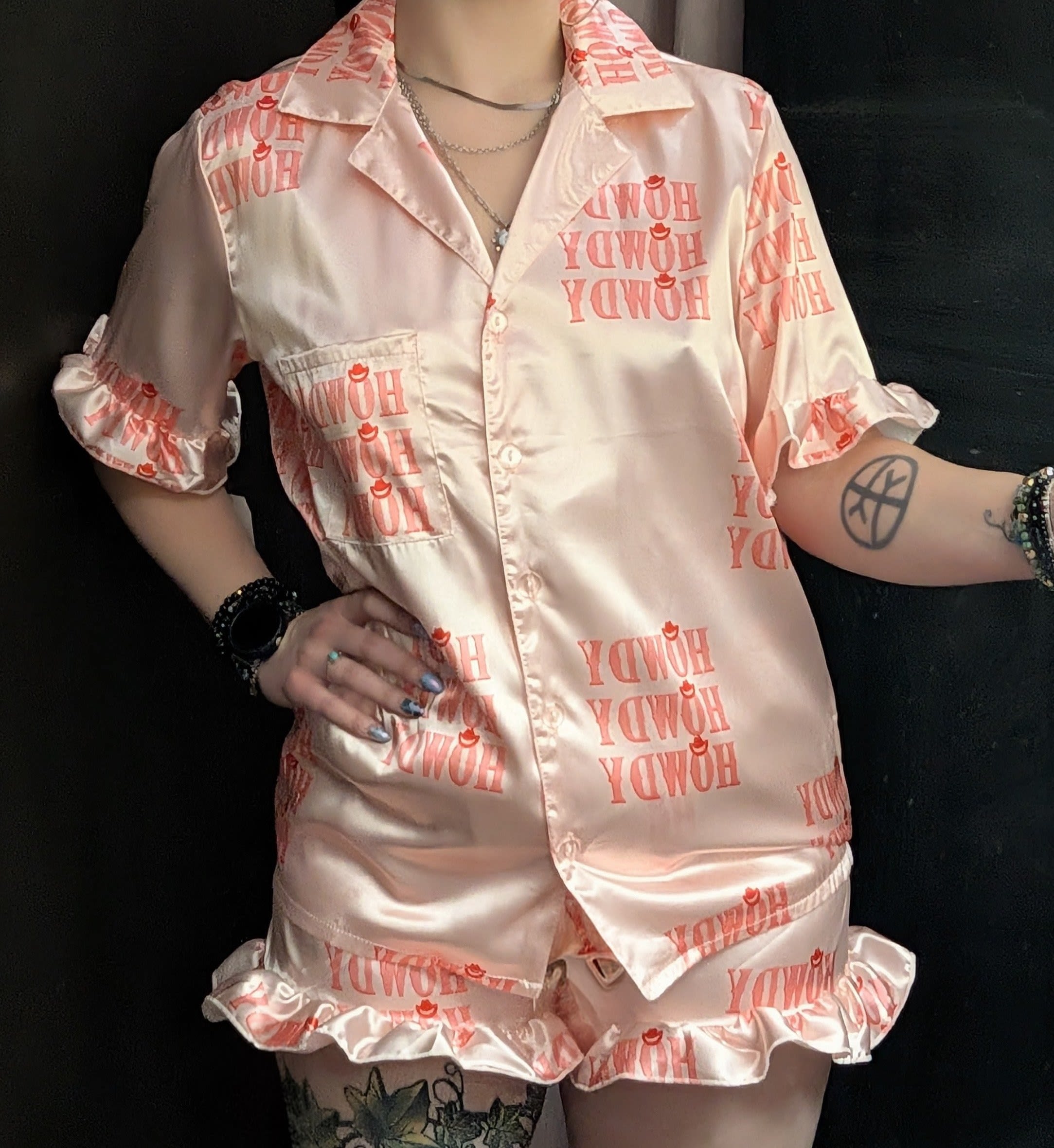Person wearing pink satin pajama set with "Howdy" print