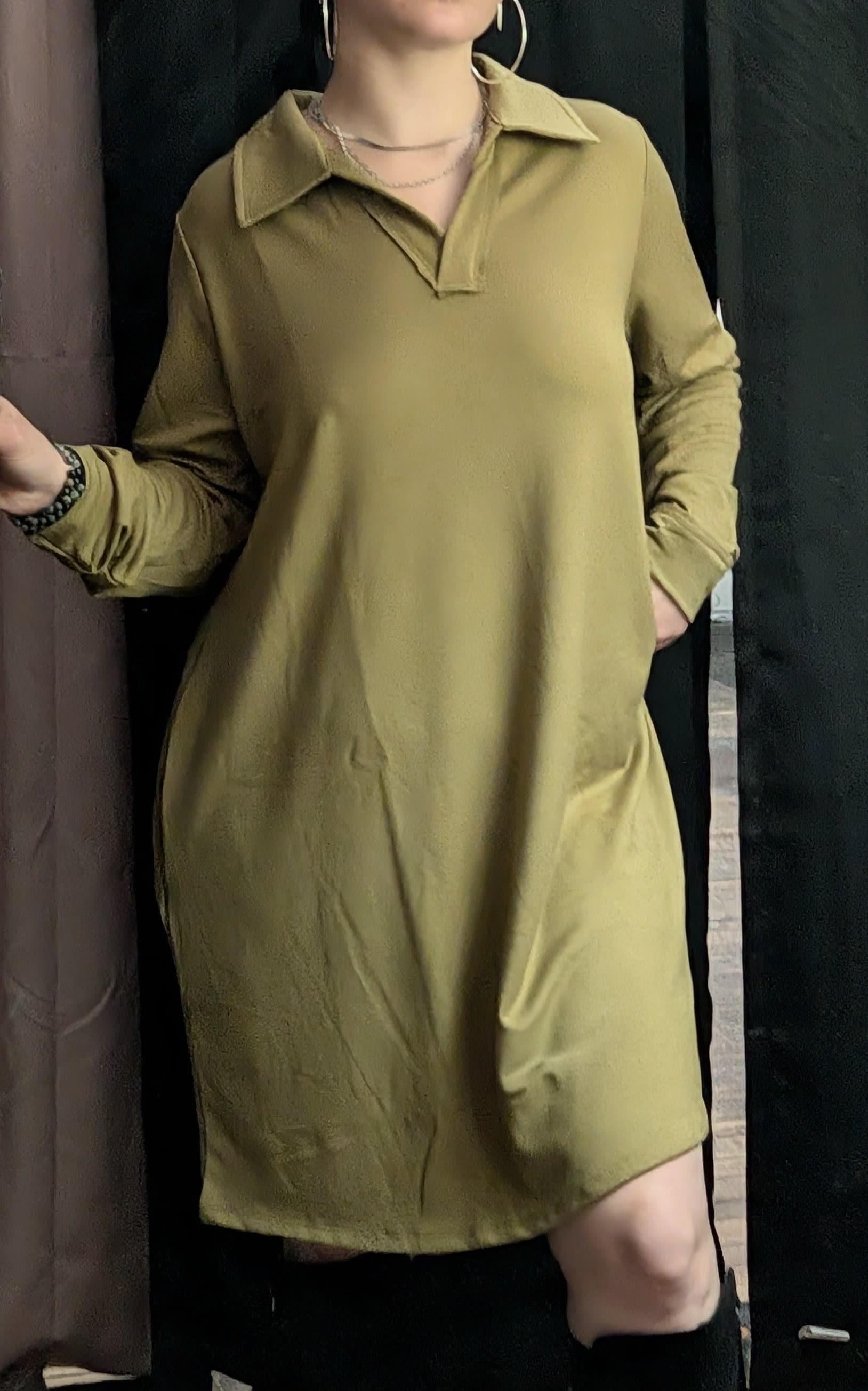 Person wearing an olive-green collared dress with long sleeves