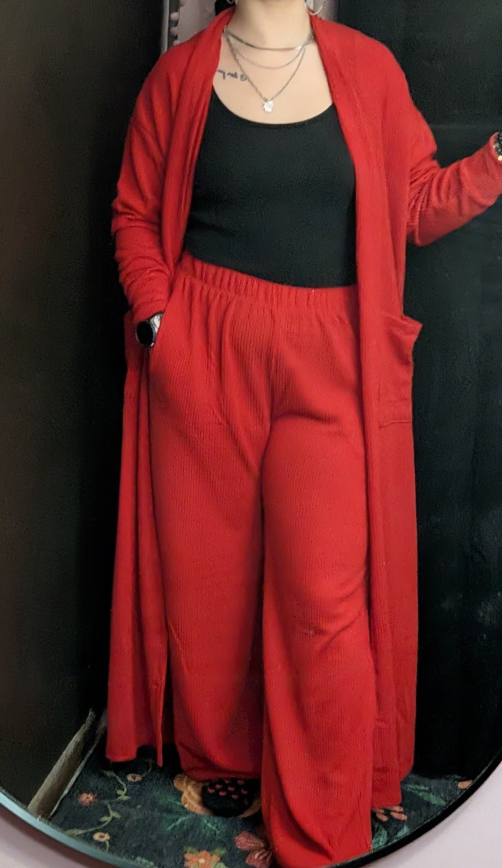 Person wearing a red cardigan and matching pants over a black top