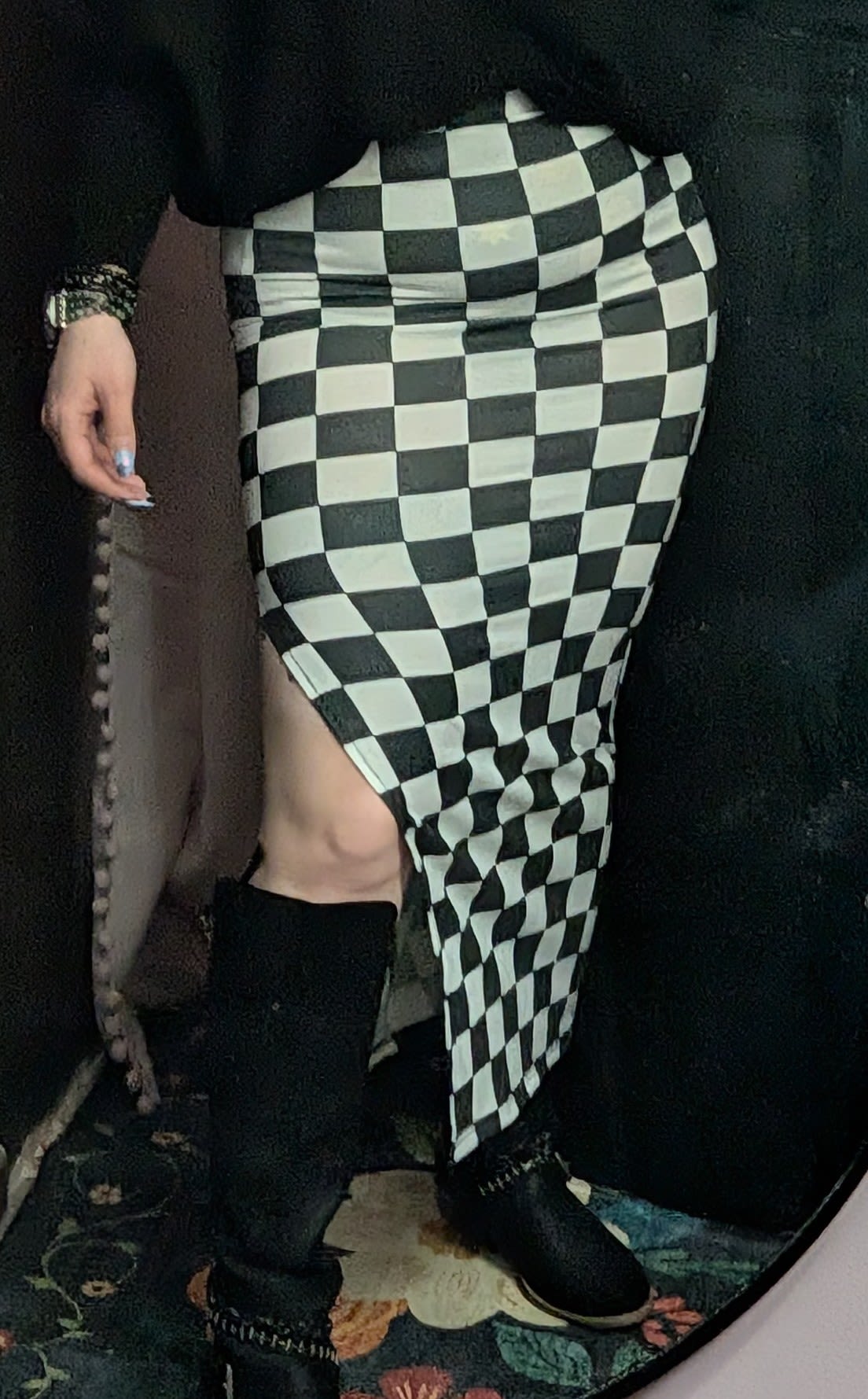 Person wearing a black-and-white checkered skirt and black boots