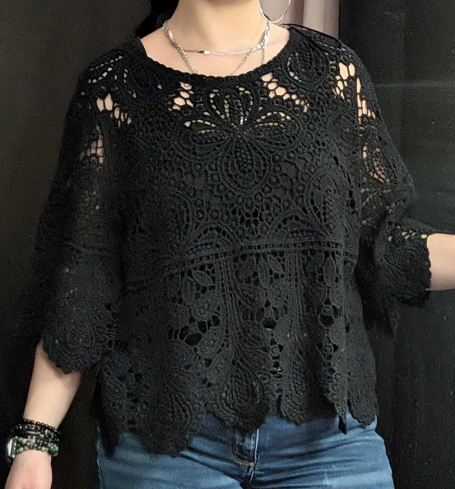 Person wearing a black lace top with blue jeans