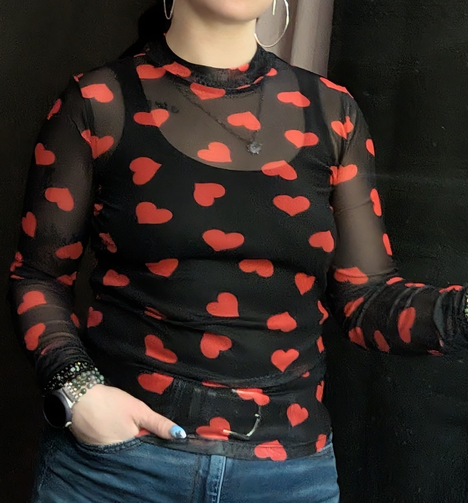 Person wearing a black sheer top with red heart pattern