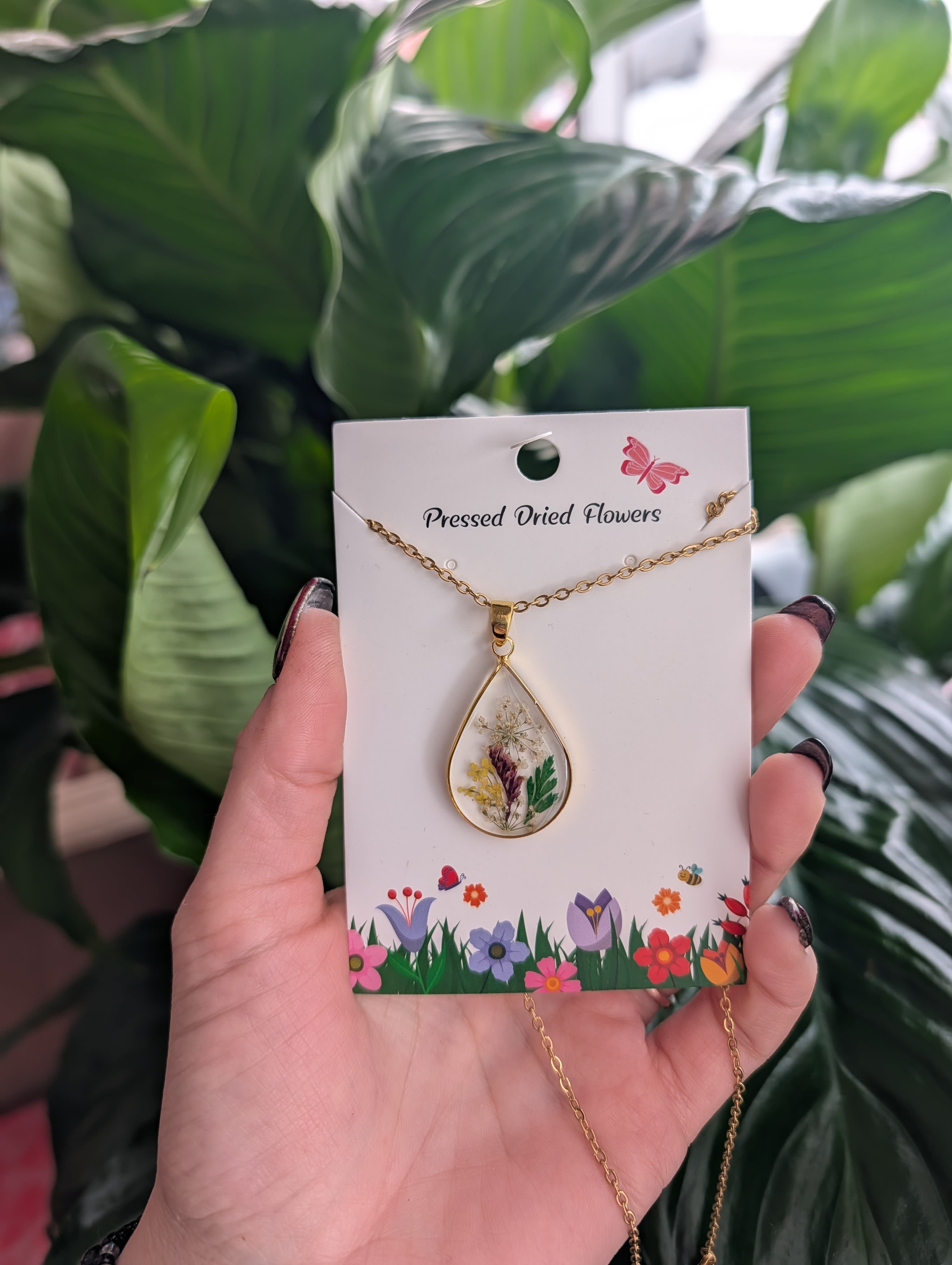 Gold teardrop necklace with pressed dried flowers on a display card