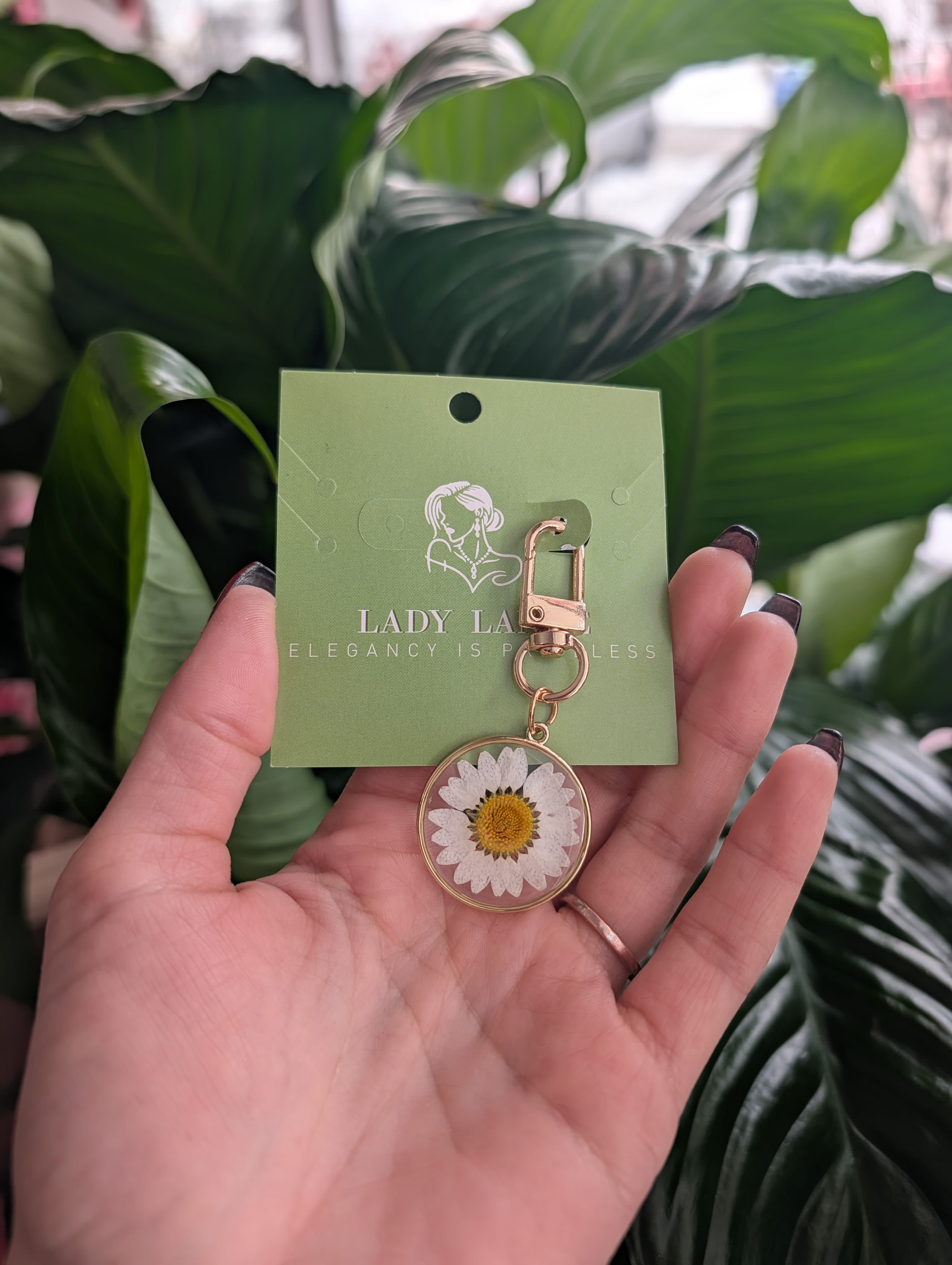 Daisy keychain charm on a green card held in a hand