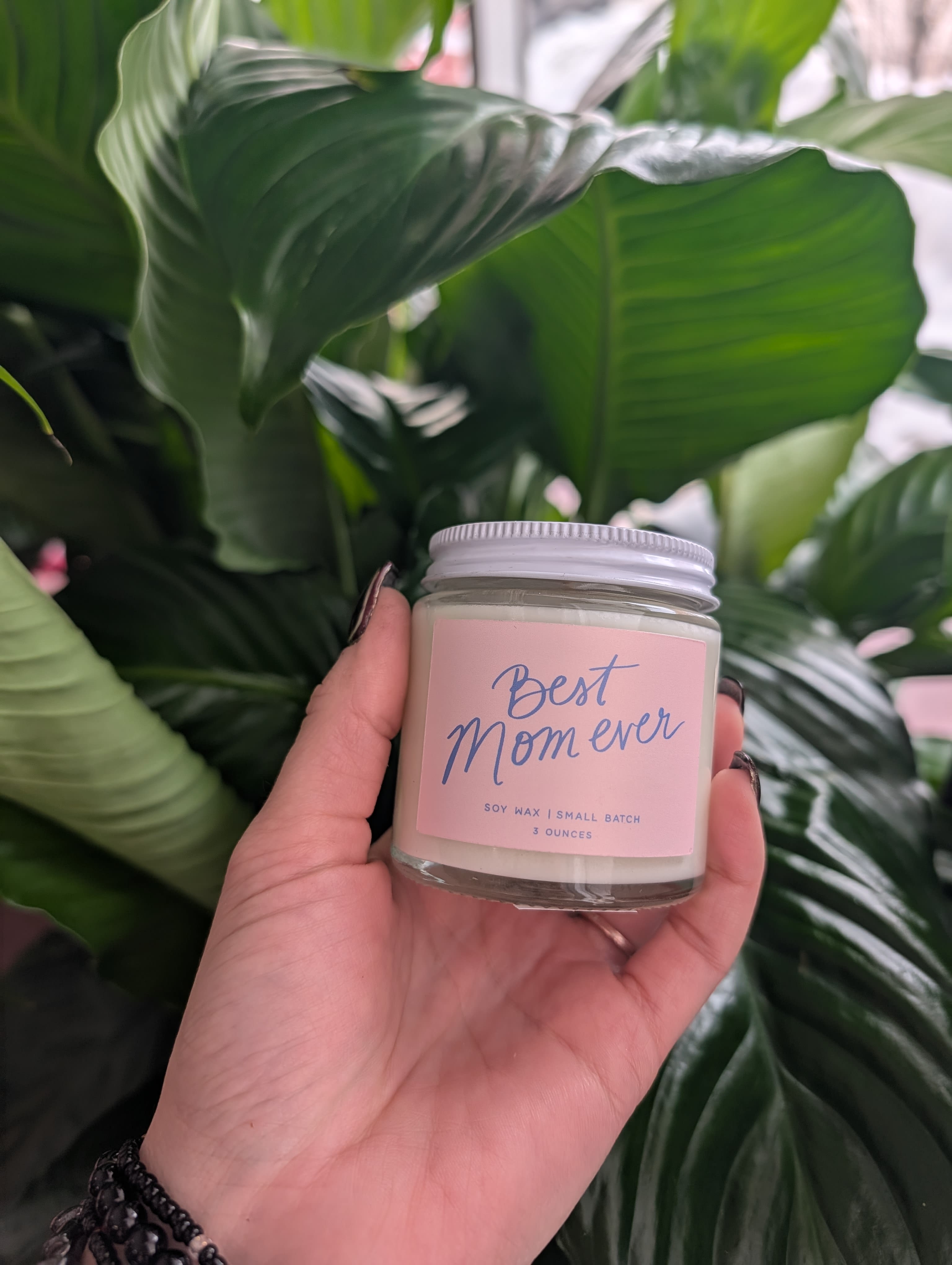 Hand holding a small candle jar labeled "Best Mom ever"