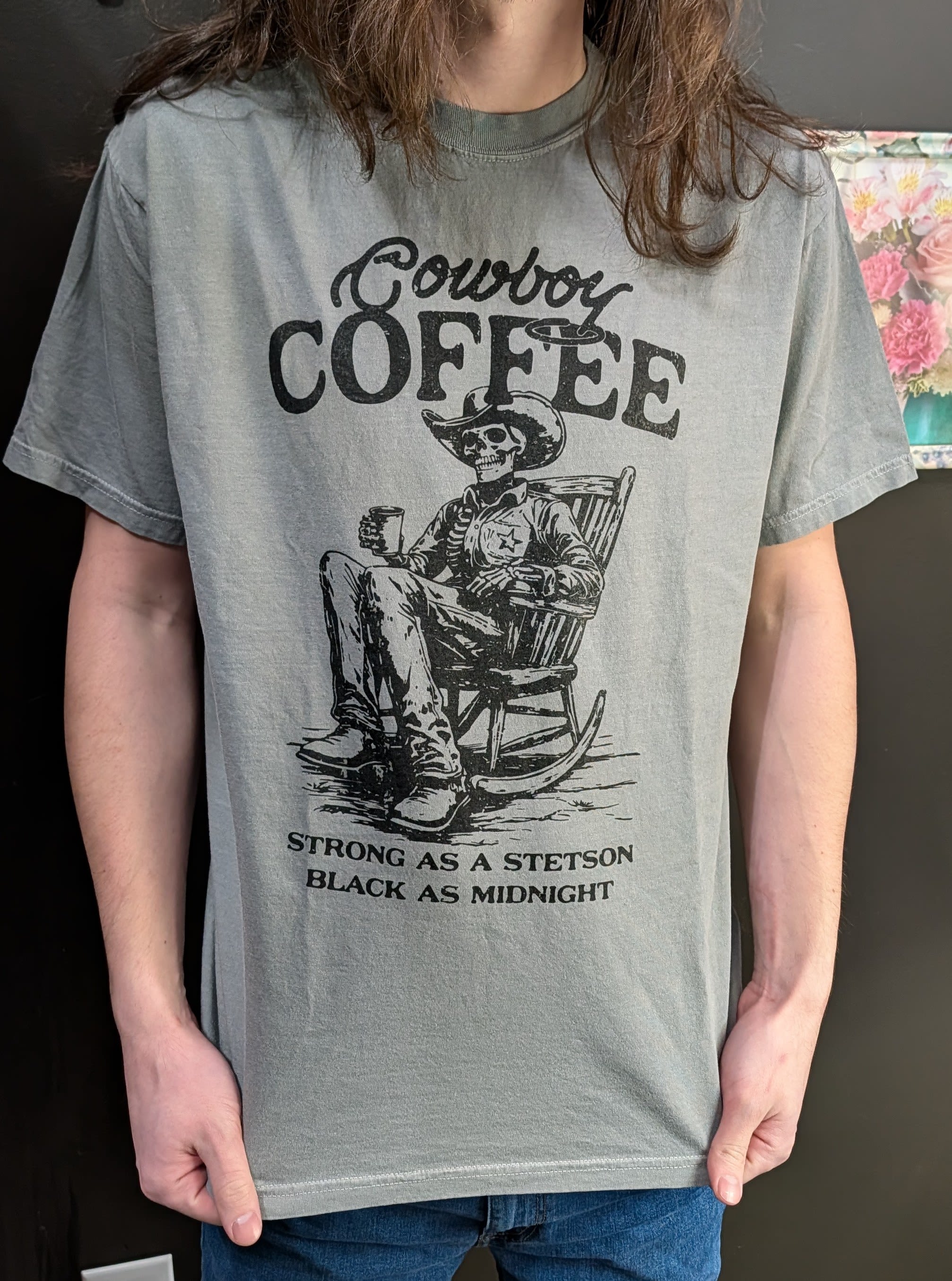 Person wearing a gray graphic T-shirt with a cowboy skeleton coffee print