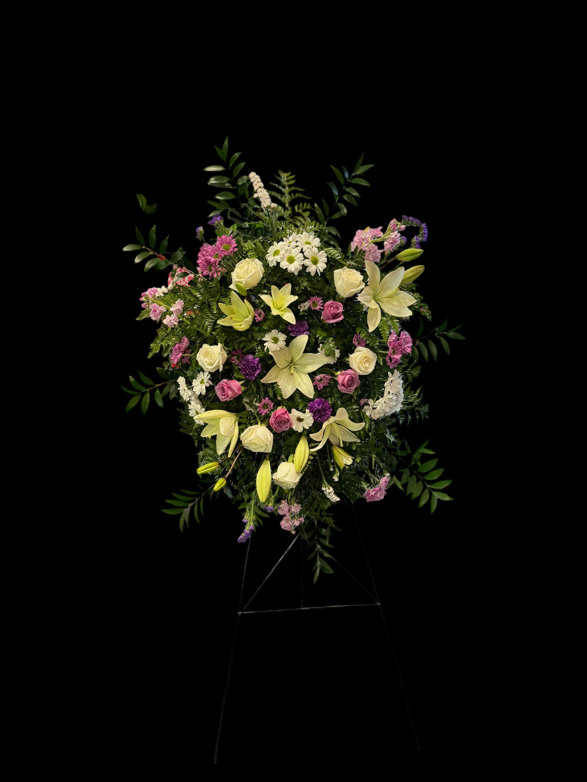 Standing floral spray with lilies, roses, and mixed blooms on an easel