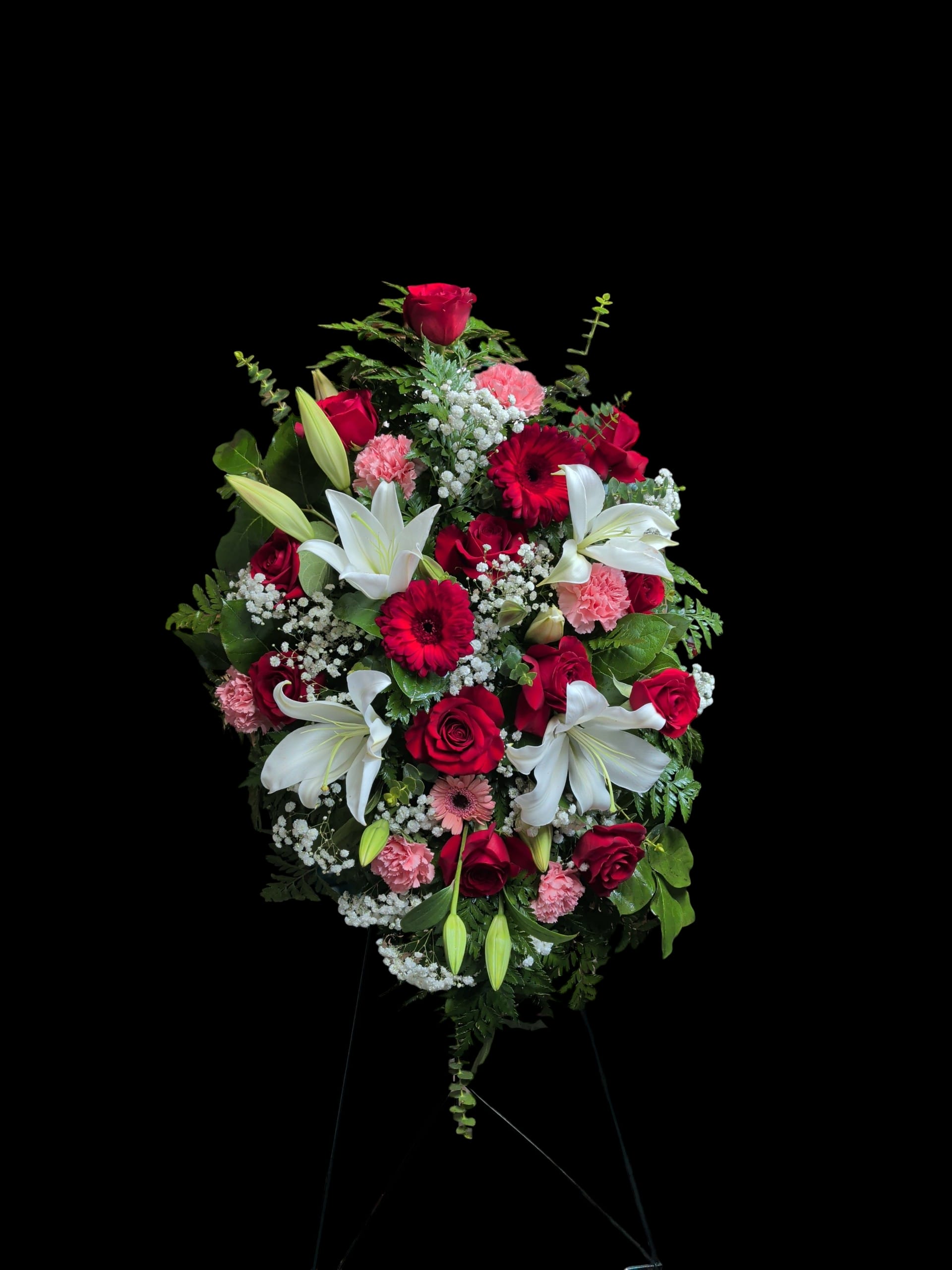 Standing floral spray with red roses, white lilies, and pink carnations
