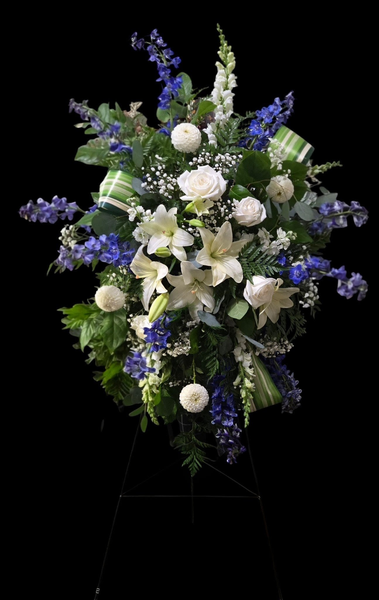 Tall white and blue floral standing spray on an easel