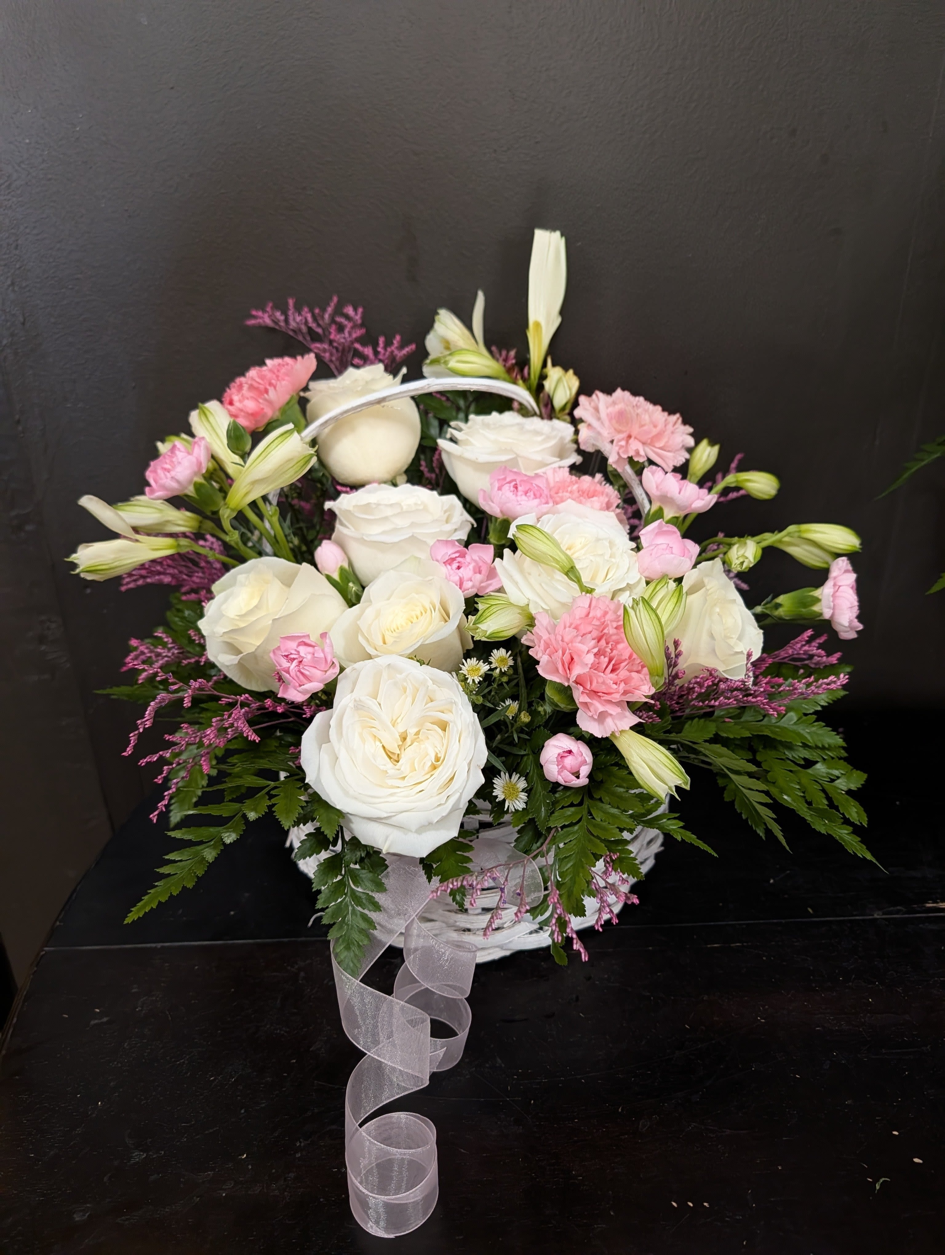 White and pink floral basket arrangement with a ribbon handle