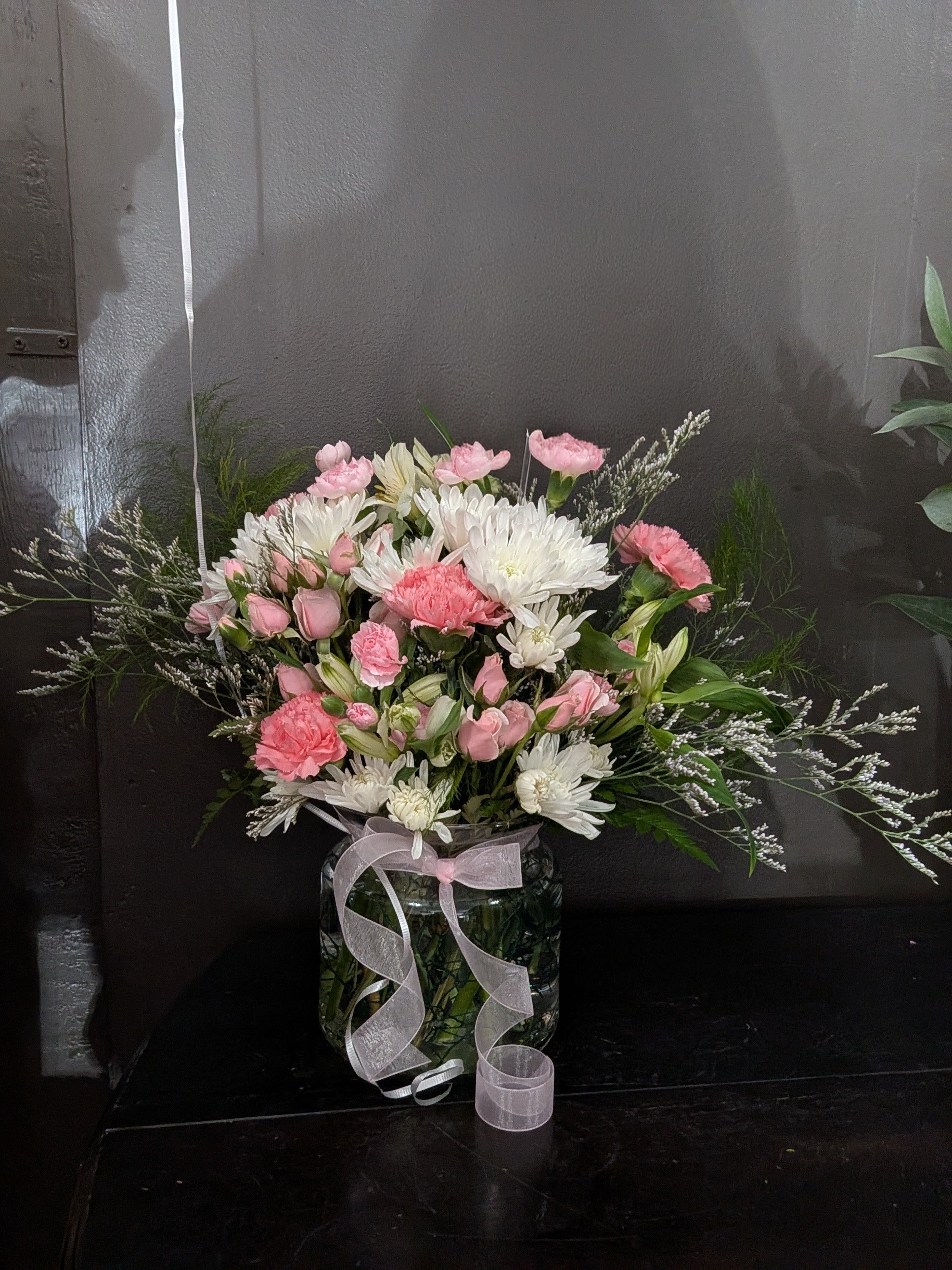 Pink and white mixed bouquet in a glass vase with a ribbon