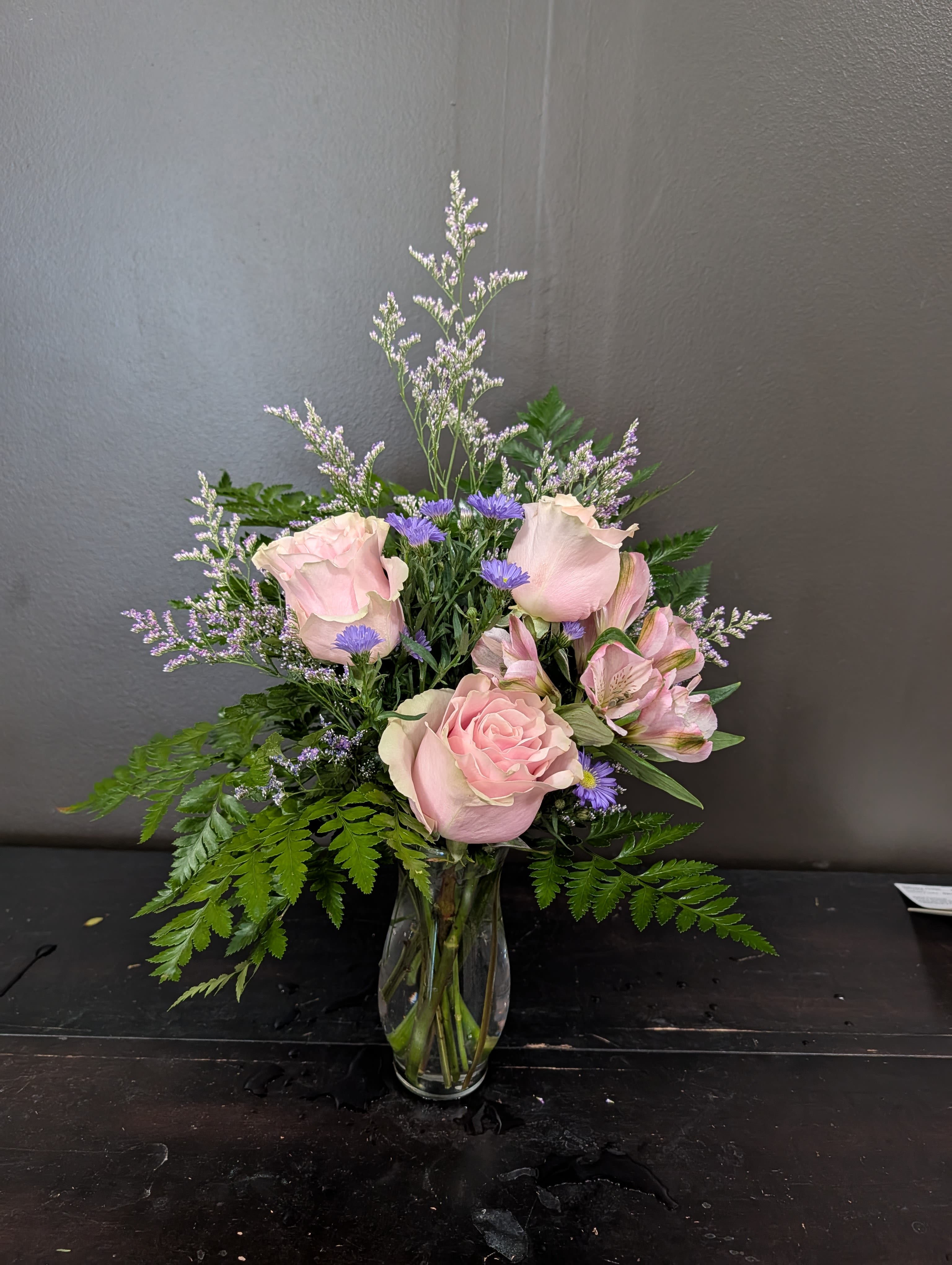 Pink roses and purple flowers in a clear glass vase
