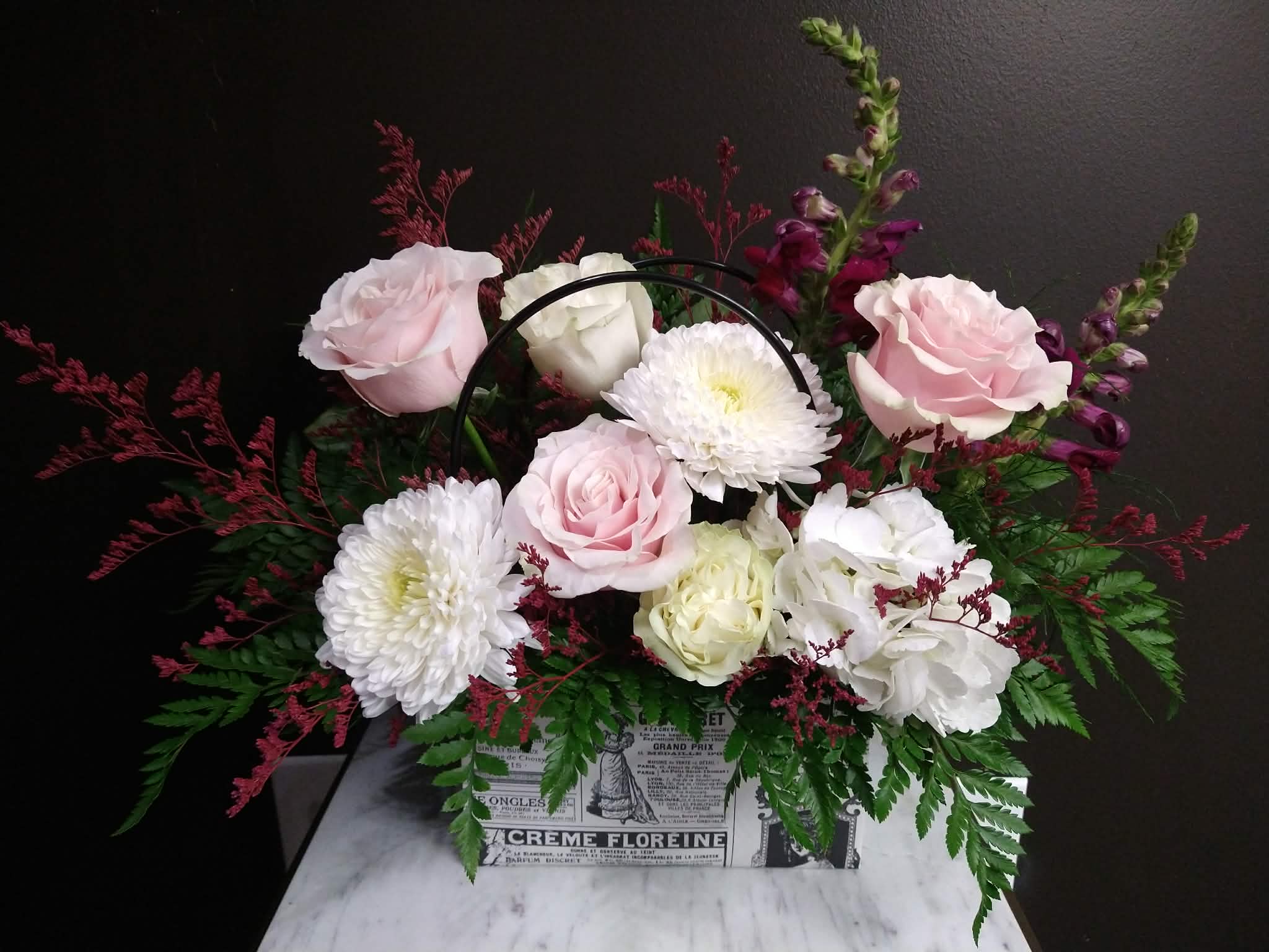 Purse-vous français - Pink and white flowers in a purse shape container with french newspaper print.